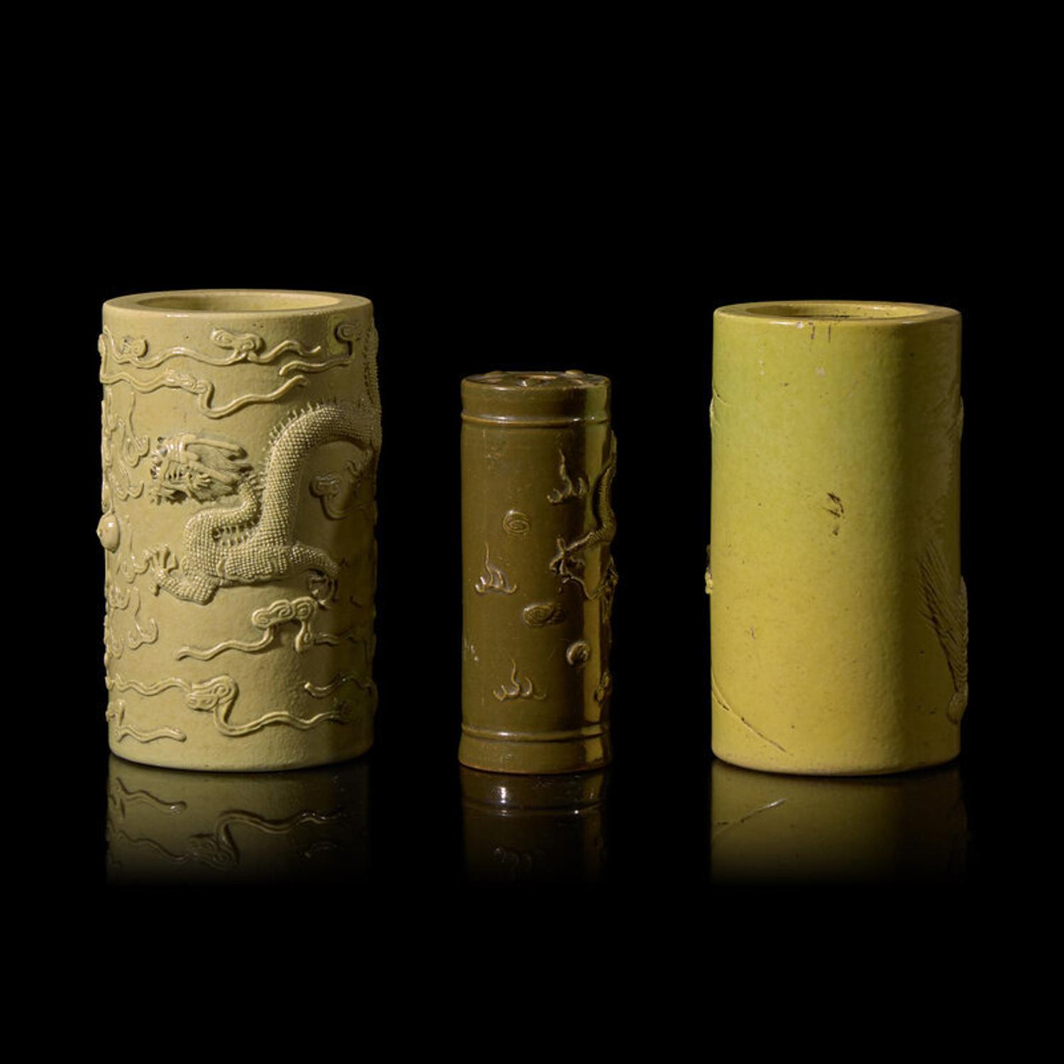 A Chinese Carved Teadust Glazed Porcelain Joss-Stick Holder and Two Carved Yellow Glazed Porcelain Brushpots, Bitong, Late Qing Dynasty-Republic Period 晚清-民國 模印雕瓷三件