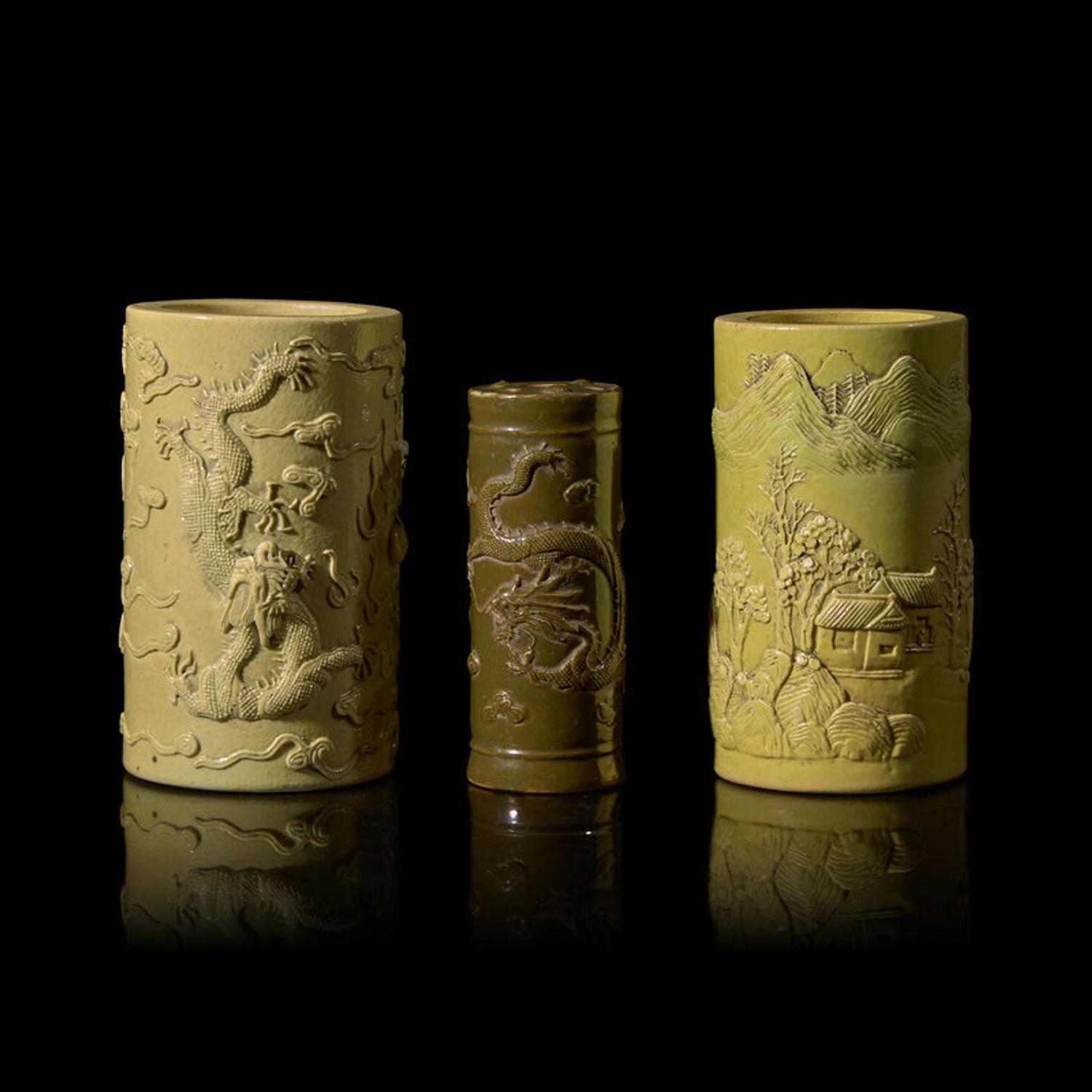 A Chinese Carved Teadust Glazed Porcelain Joss-Stick Holder and Two Carved Yellow Glazed Porcelain Brushpots, Bitong, Late Qing Dynasty-Republic Period 晚清-民國 模印雕瓷三件