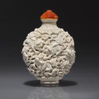 A Chinese Molded White-Glazed Porcelain "Buddhist Lions" Snuff Bottle, Qing Dynasty, Jiaqing Mark and of the Period — 清嘉慶 白釉模印鏤雕獅戲繡球圖鼻煙壺
