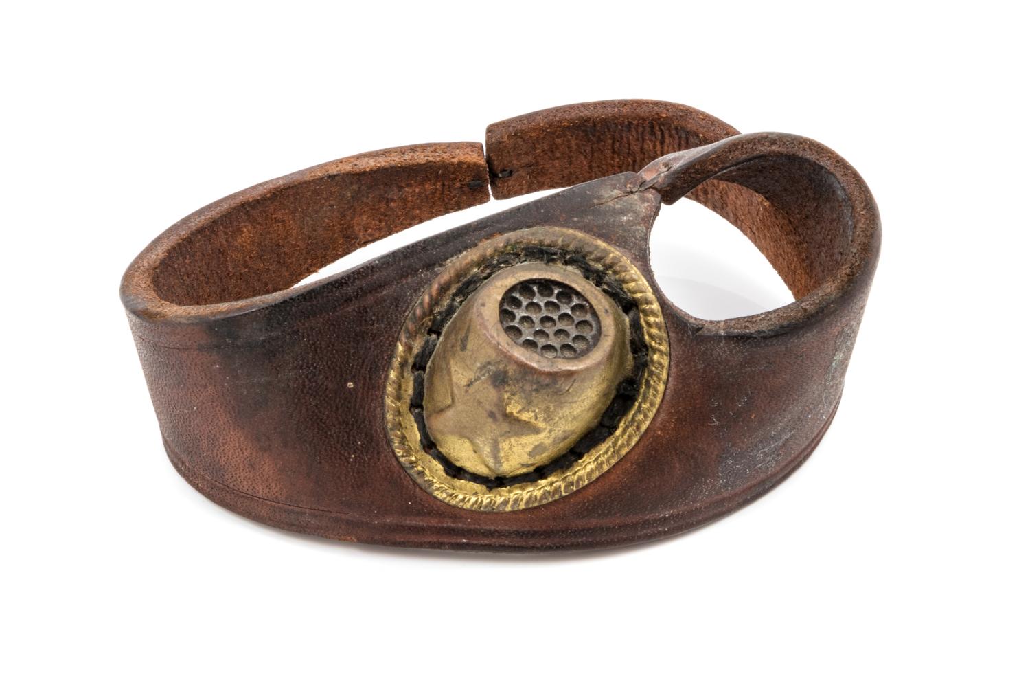 A Leather and Gilt Metal Sailmaker Palm Thimble, , the thimble having a gilt metal finish, attached to a leather hand strap.