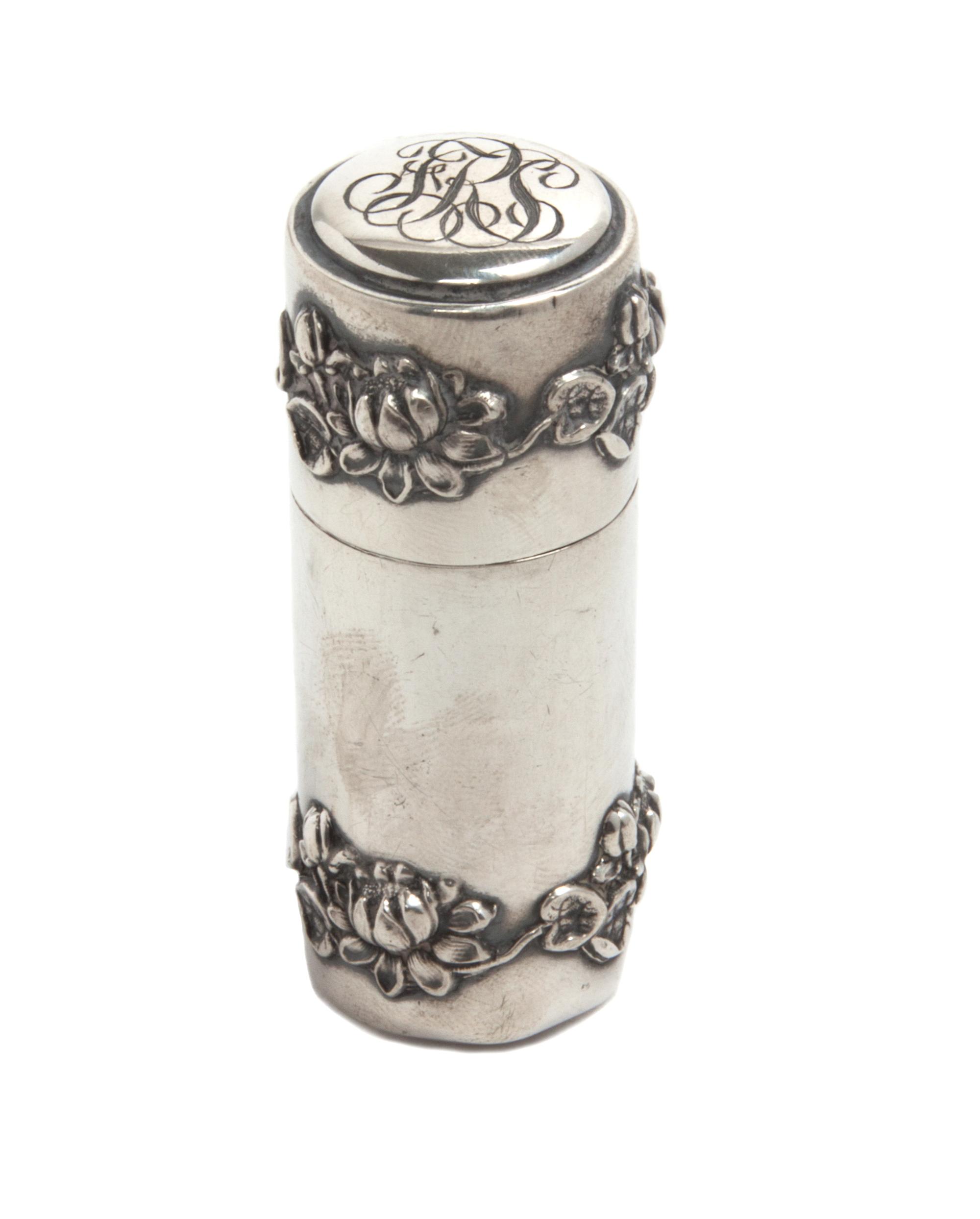 A Silver Cylindrical Box, , the lid with a script monogram, the body applied with bands of lotus at the top and bottom.