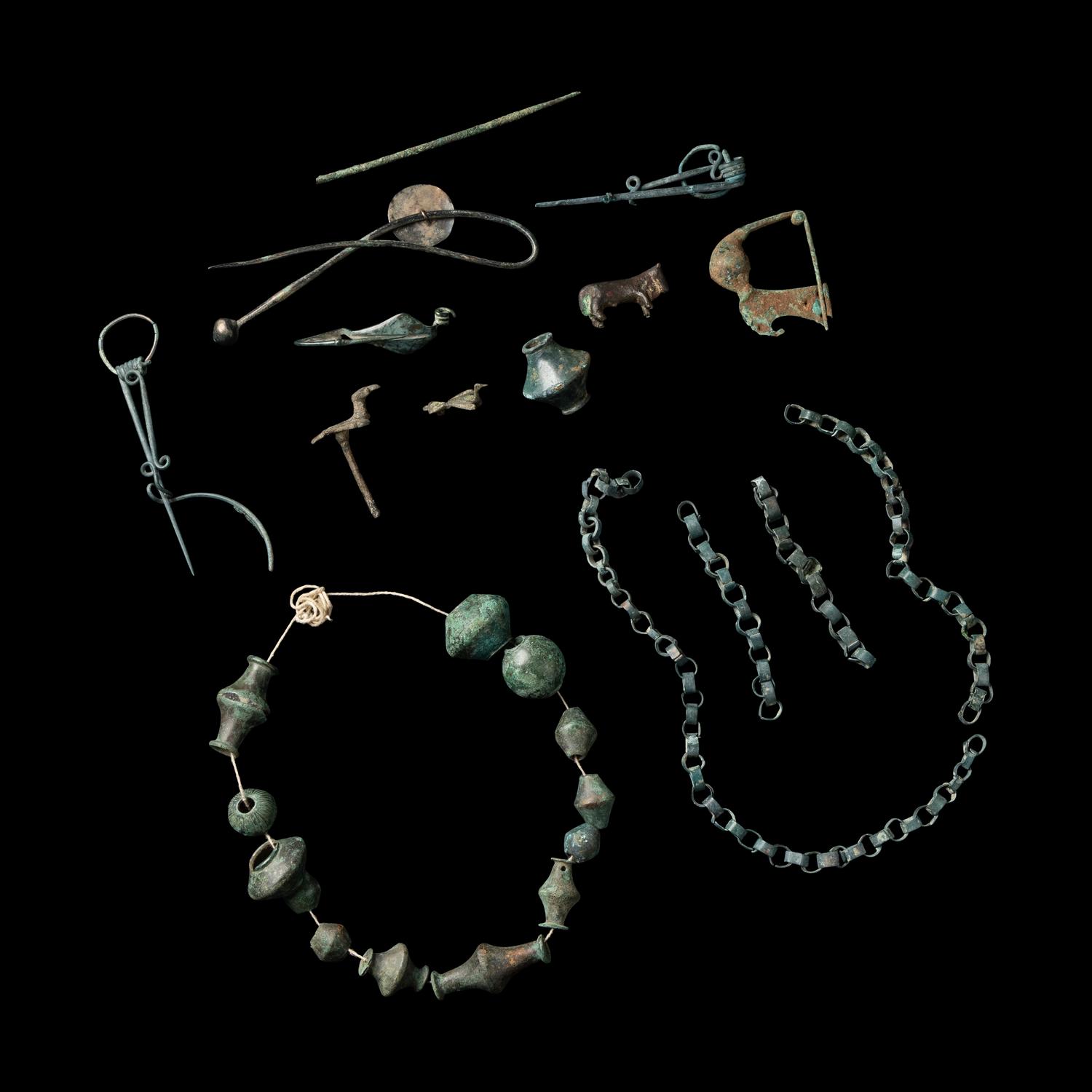 A Group of European and Luristan Bronze Fragmentary Fibulae, Beads, and Chains