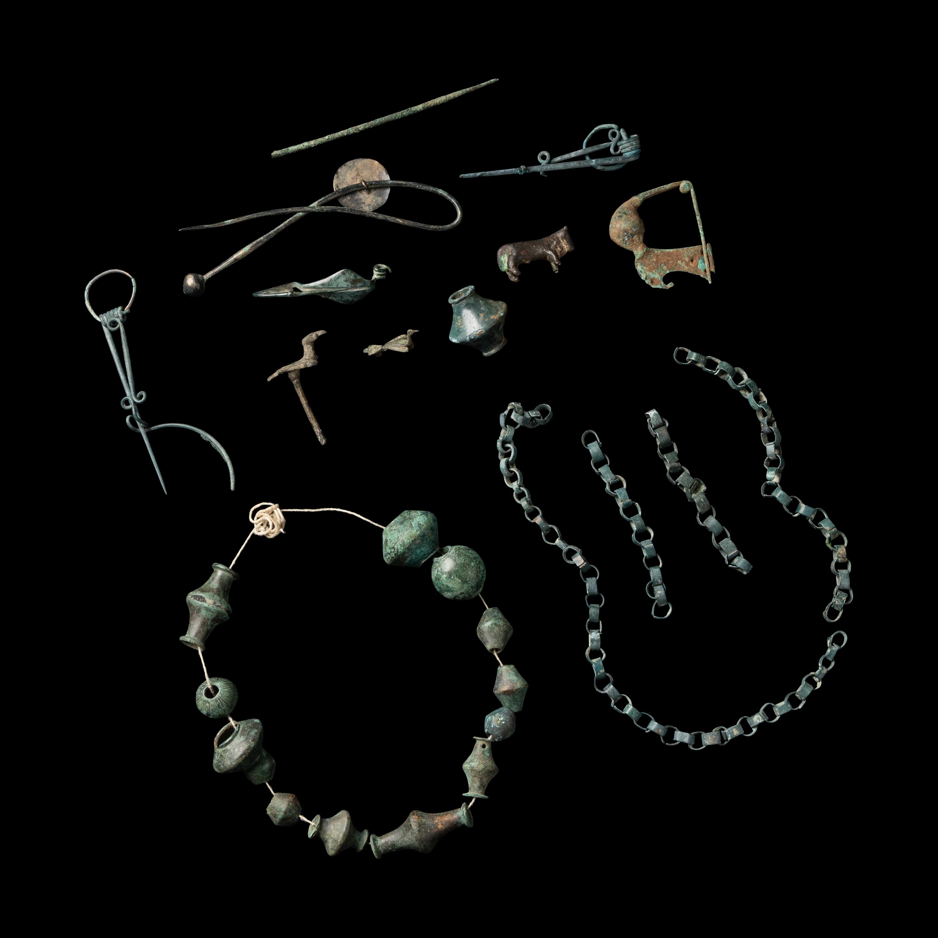 A Group of European and Luristan Bronze Fragmentary Fibulae, Beads, and Chains