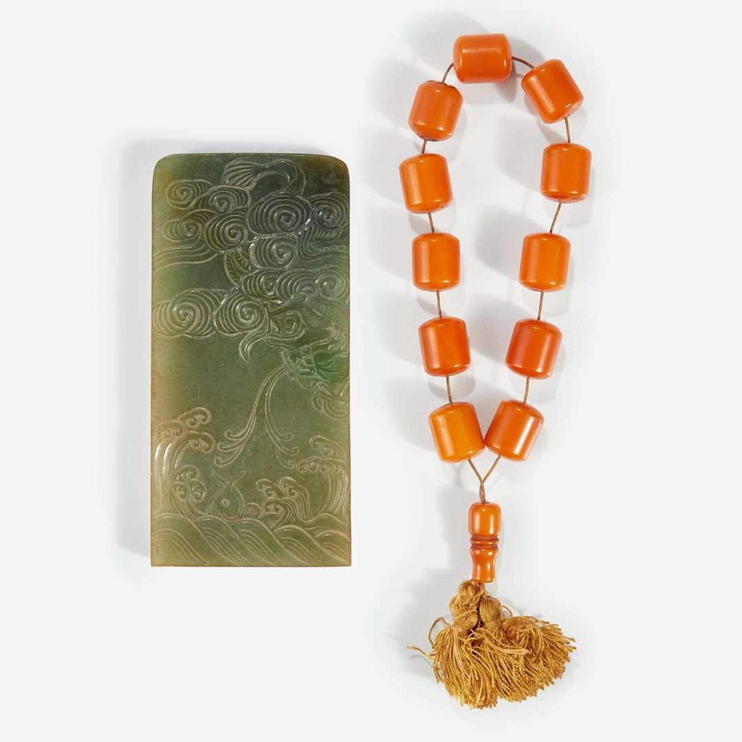 A Chinese carved jadeite "Dragon" plaque and a part set of twelve amber beads