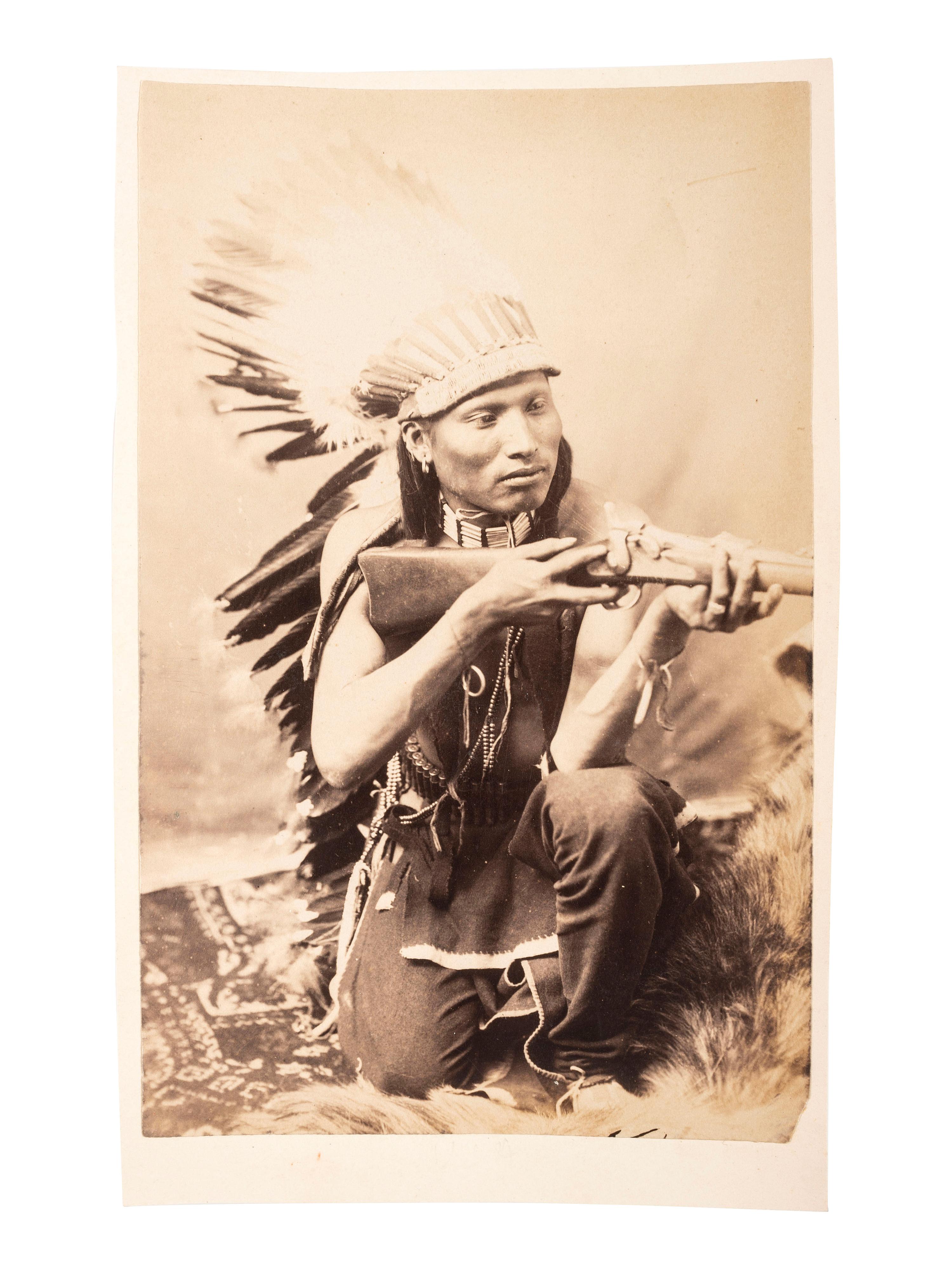[NATIVE AMERICANS]. [BAKER & JOHNSTON, photographers]. Cabinet card of an Arapaho kneeling with rifle. [Evanston, Wyoming: ca 1890s].