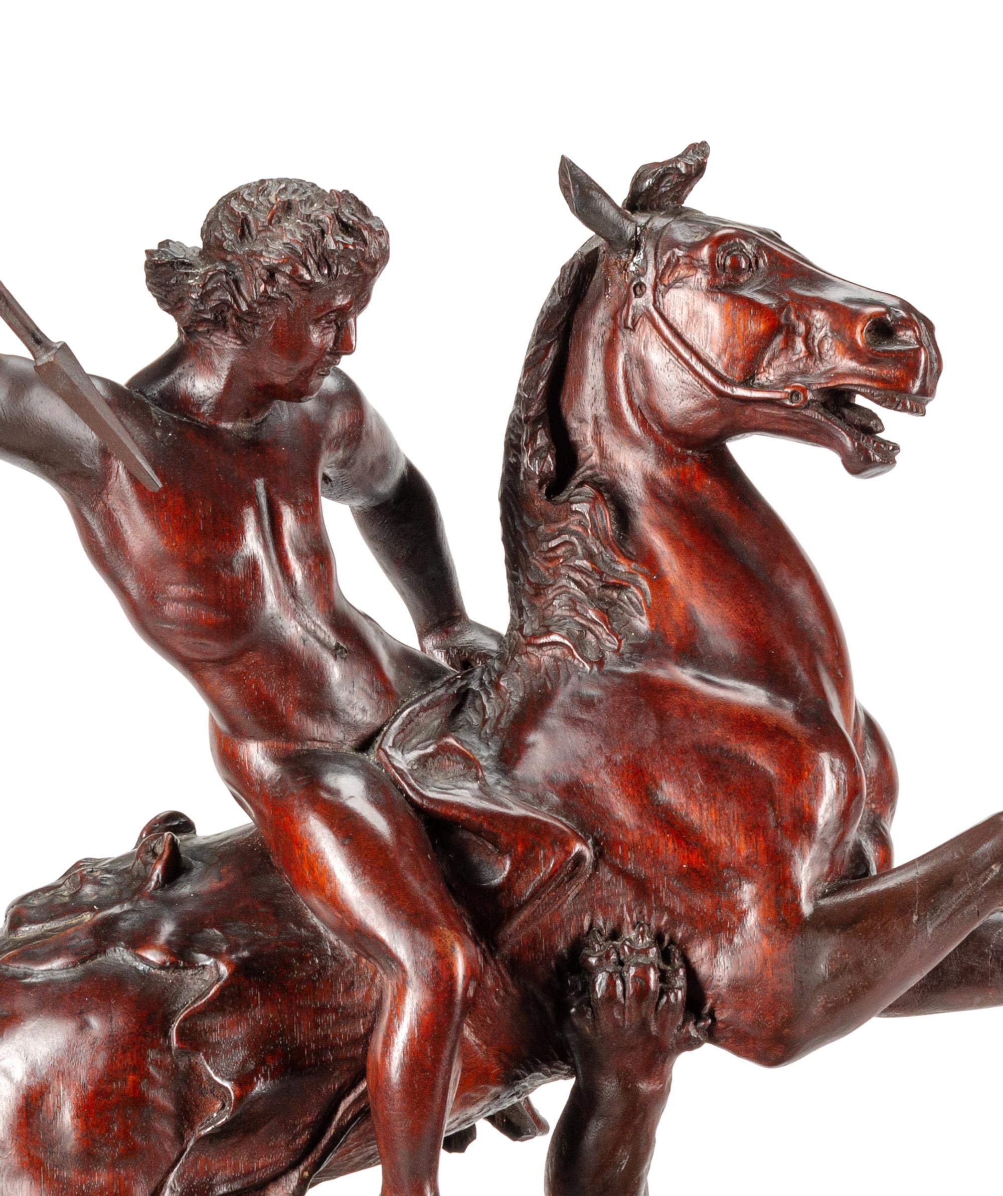 A Carved Wood Figural Group of a Young Man on Horseback Slaying a Lion
