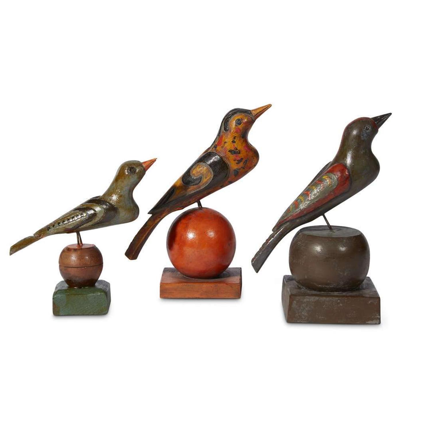 Three carved and painted birds on spherical stands in the manner of Schnockschnitzler Simmons (active 1895-1910) Robert Stauffer, late 20th century