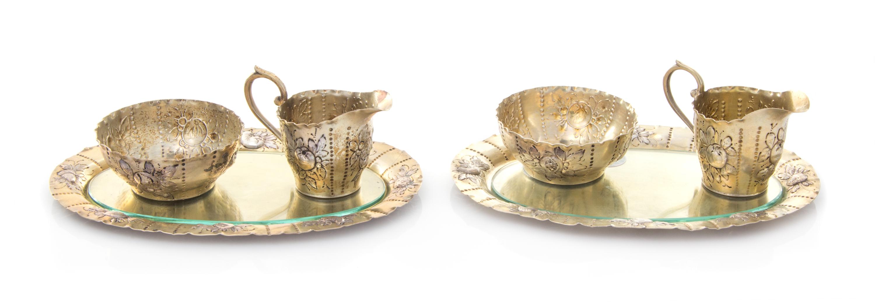 A Pair of German Silver-Gilt Creamer and Sugar Sets, , comprising a creamer, sugar and underplate, each having floral and foliate repou