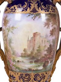 A Pair of Sèvres Style Gilt Bronze Mounted Painted and Parcel Gilt Porcelain Urns