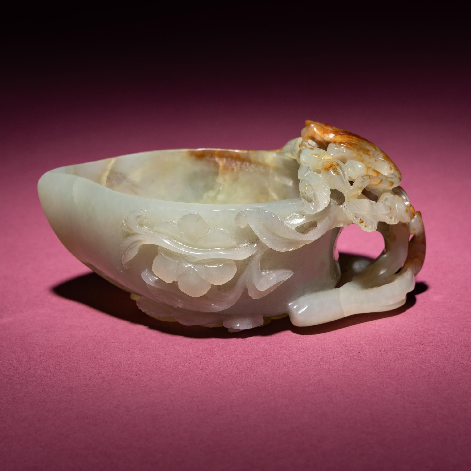 A Chinese Russet and Celadon Jade ‘Magpie and Plum Blossoms’ Peach-Form Coupe, 19th Century — 清晚期 青白玉帶皮喜上眉梢桃形杯