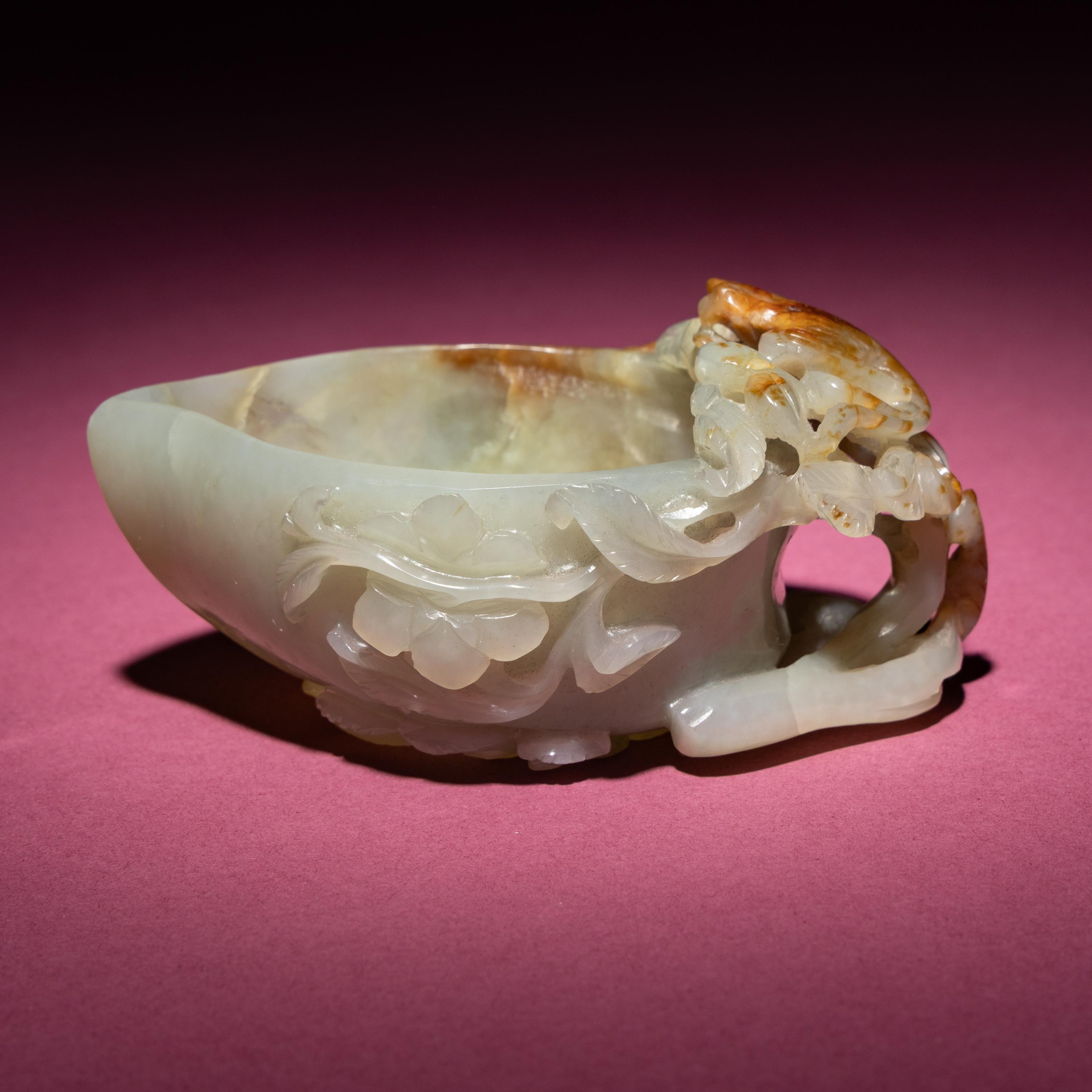 A Chinese Russet and Celadon Jade ‘Magpie and Plum Blossoms’ Peach-Form Coupe, 19th Century — 清晚期 青白玉帶皮喜上眉梢桃形杯