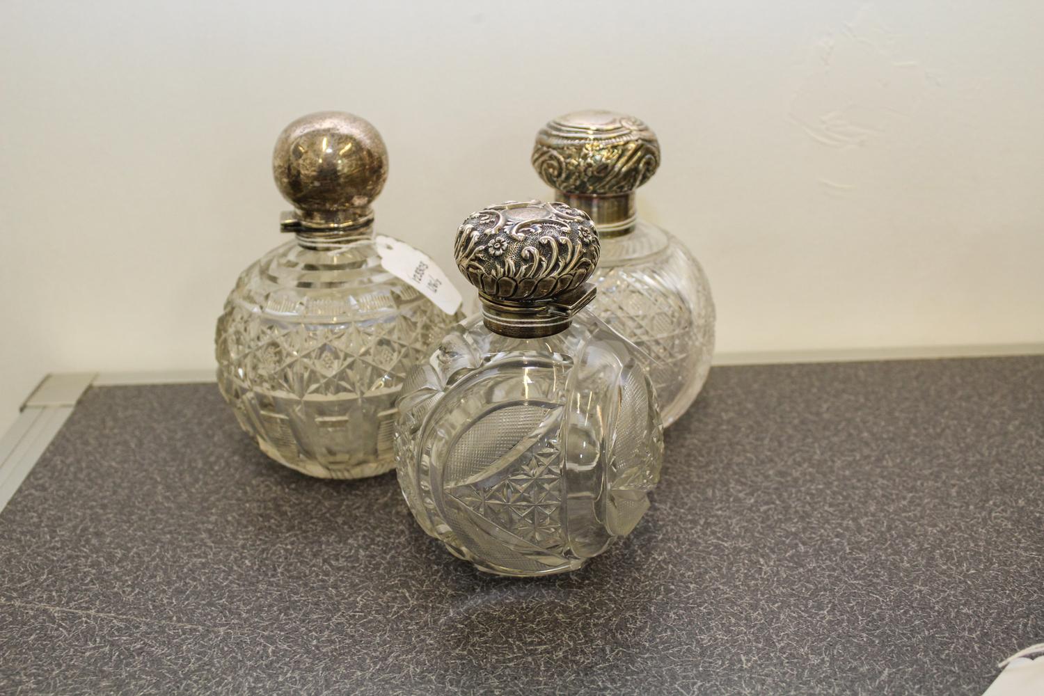 A Group of Three English Silver and Cut Glass Perfume Bottles, Makers marks obscured, Birmingham, each having a spherical glass body wi