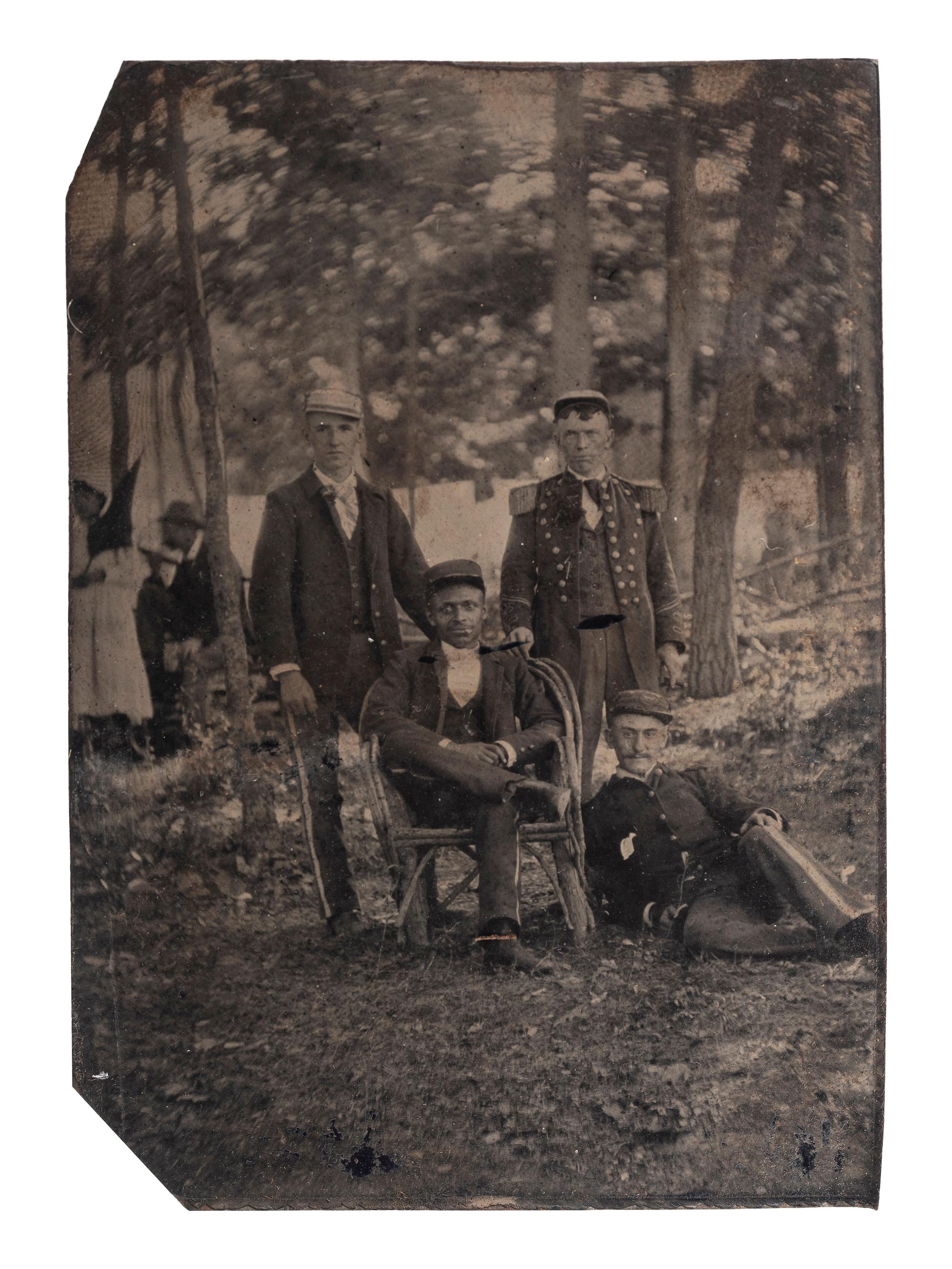[AFRICAN AMERICANA] -- [EARLY PHOTOGRAPHY]. Sixth plate outdoor tintype of an African American man with white men in uniform. Ca late 19th century.
