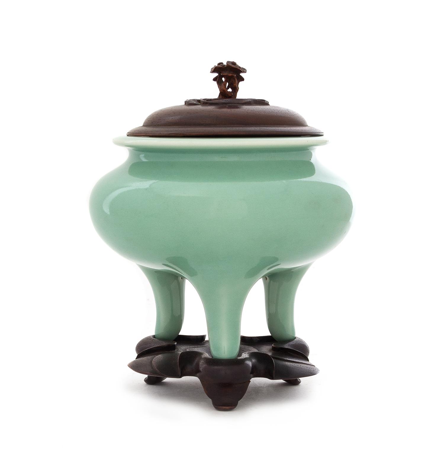 A Japanese Celadon Glazed Porcelain Tripod Incense Burner Height 4 3/4 inches. — PORCELAIN: EARLY 20TH CENTURYWOOD COVER AND STAND: CHINESE, 19TH CENTURY