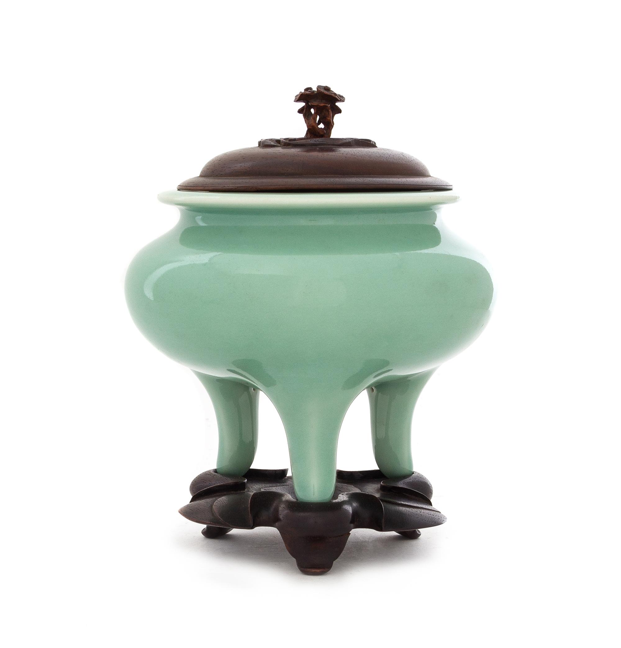 A Japanese Celadon Glazed Porcelain Tripod Incense Burner Height 4 3/4 inches. — PORCELAIN: EARLY 20TH CENTURYWOOD COVER AND STAND: CHINESE, 19TH CENTURY
