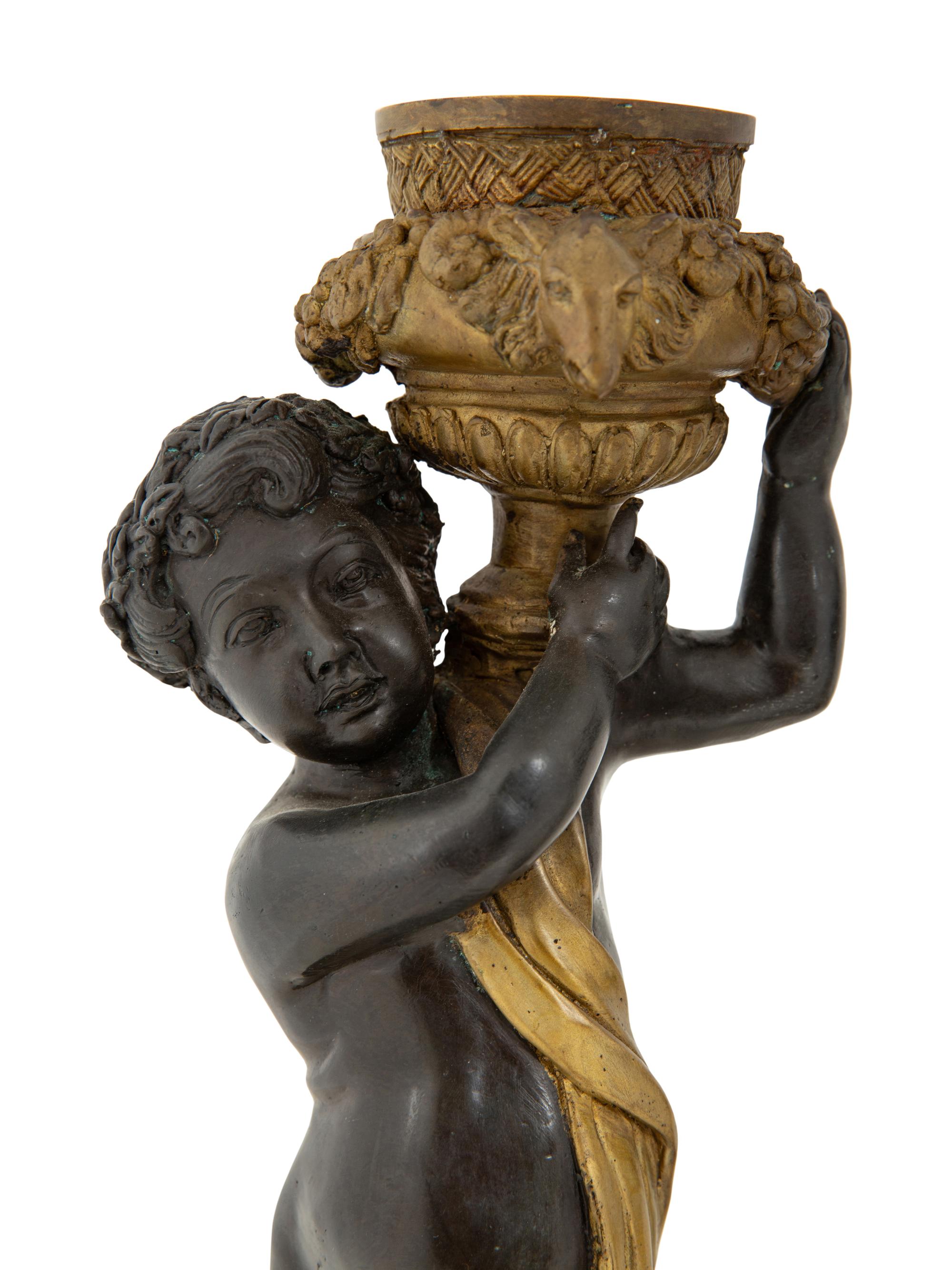 A Pair of Parcel Gilt Cast Metal Putti Candlesticks