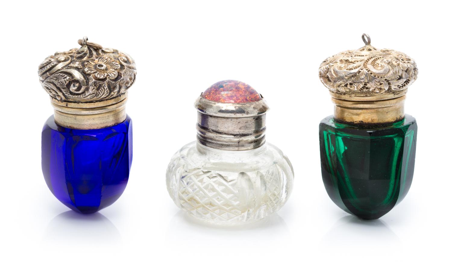 A Group of Three Silver Mounted Glass Scent Bottles, Apparently Unmarked, comprising two colored glass examples and one clear example.