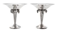 A Pair of Silver Compotes, , after the design by Georg Jensen, each having a flared bowl above pendant grape clusters and a twist stem,