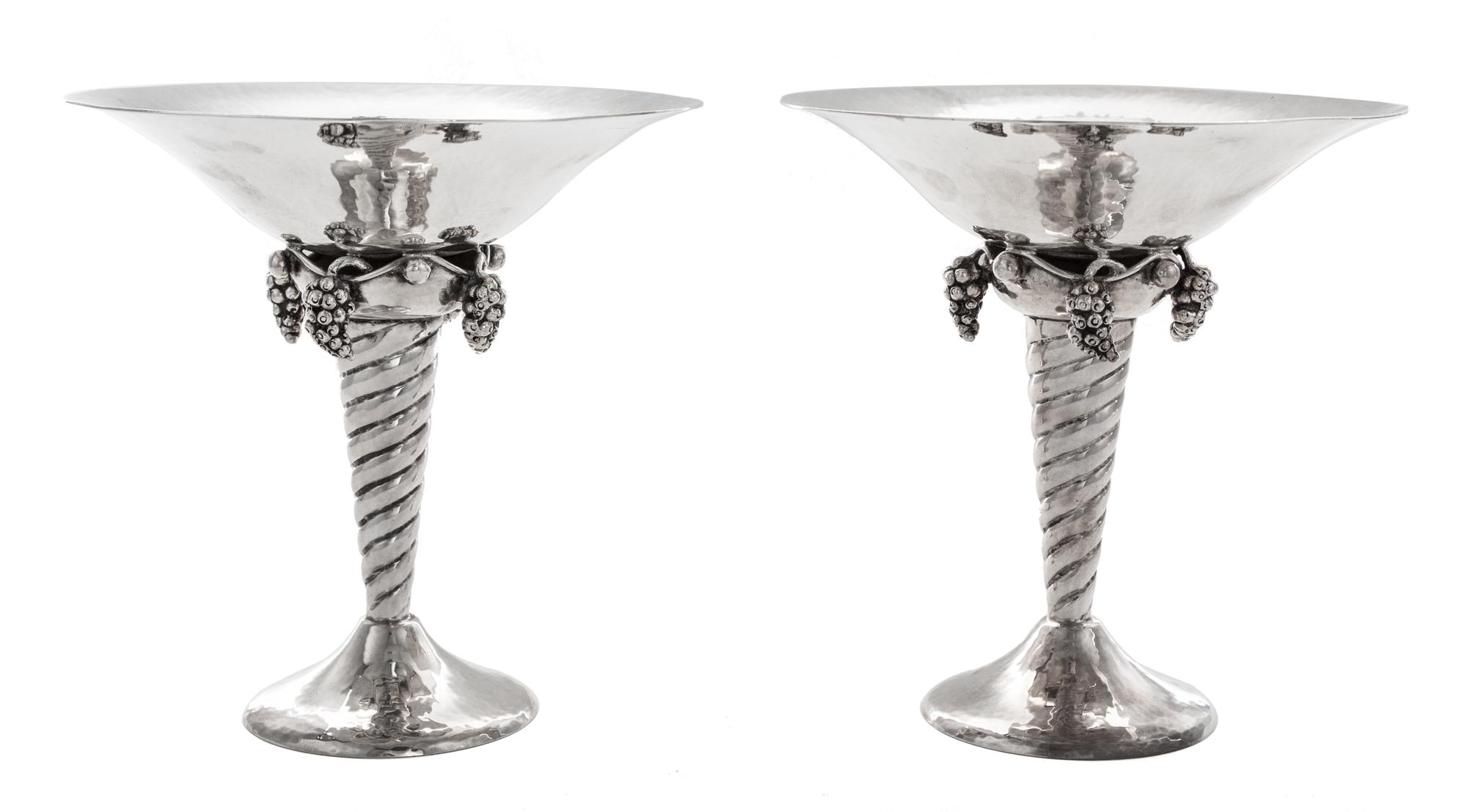 A Pair of Silver Compotes, , after the design by Georg Jensen, each having a flared bowl above pendant grape clusters and a twist stem,