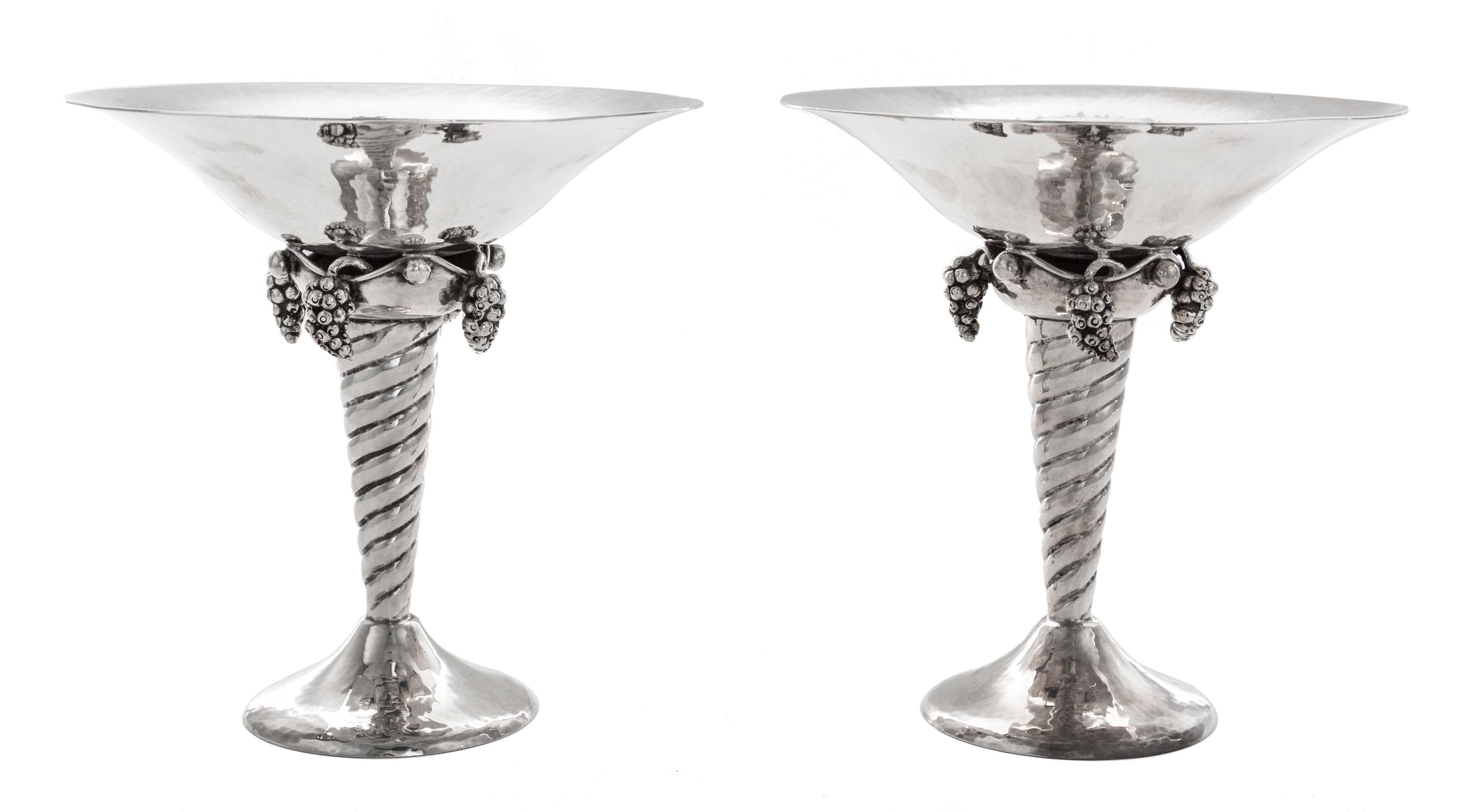 A Pair of Silver Compotes, , after the design by Georg Jensen, each having a flared bowl above pendant grape clusters and a twist stem,