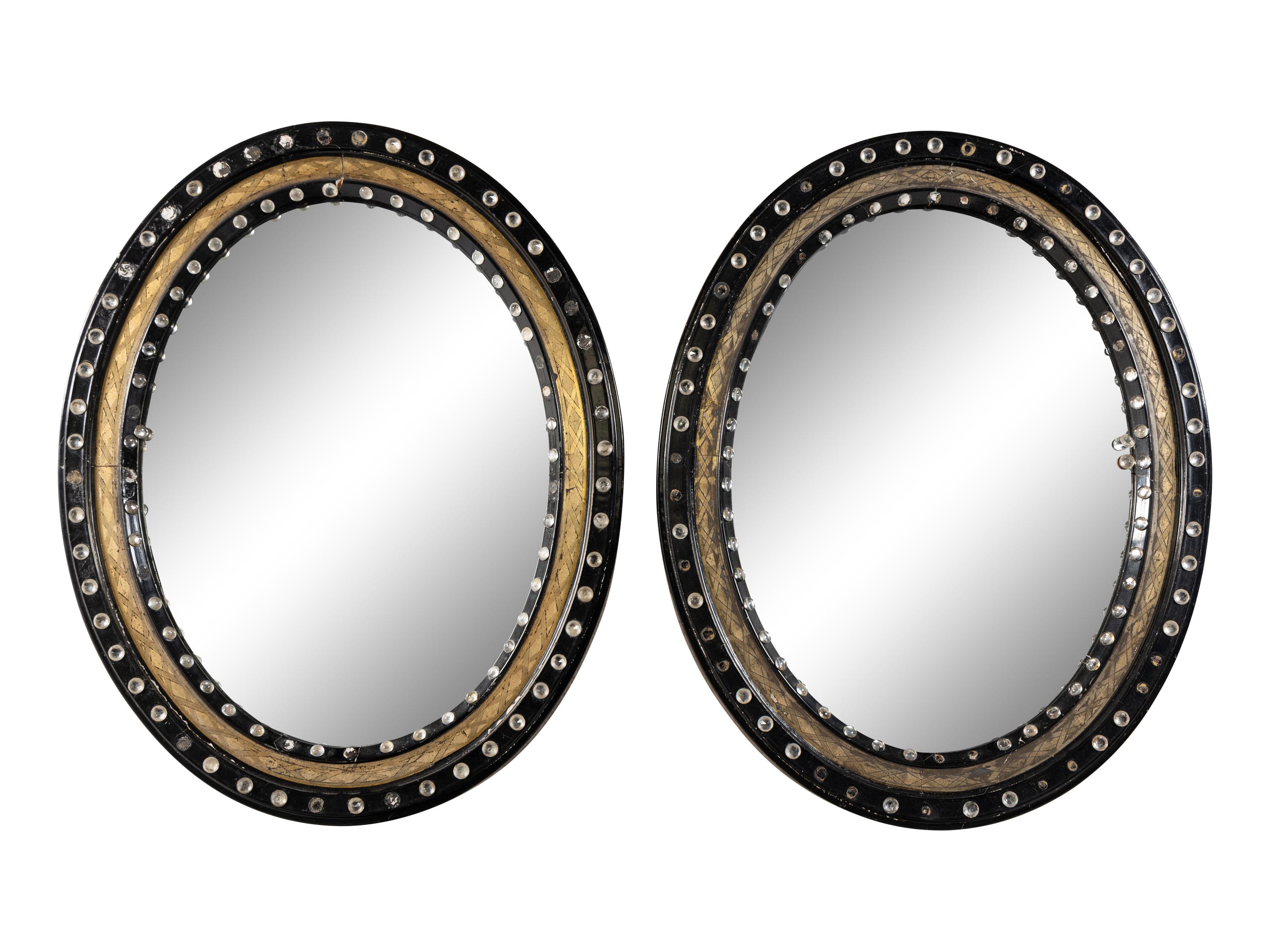 A Pair of Irish Ebonized and Parcel-Gilt Oval Mirrors