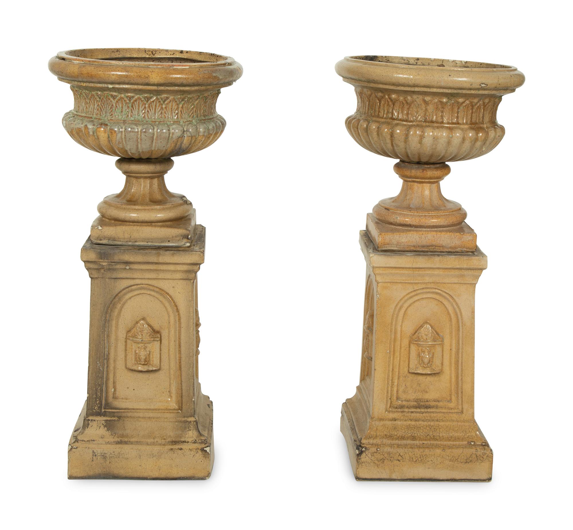 A Pair of Continental Ceramic Urns on Pedestals — EARLY 20TH CENTURY