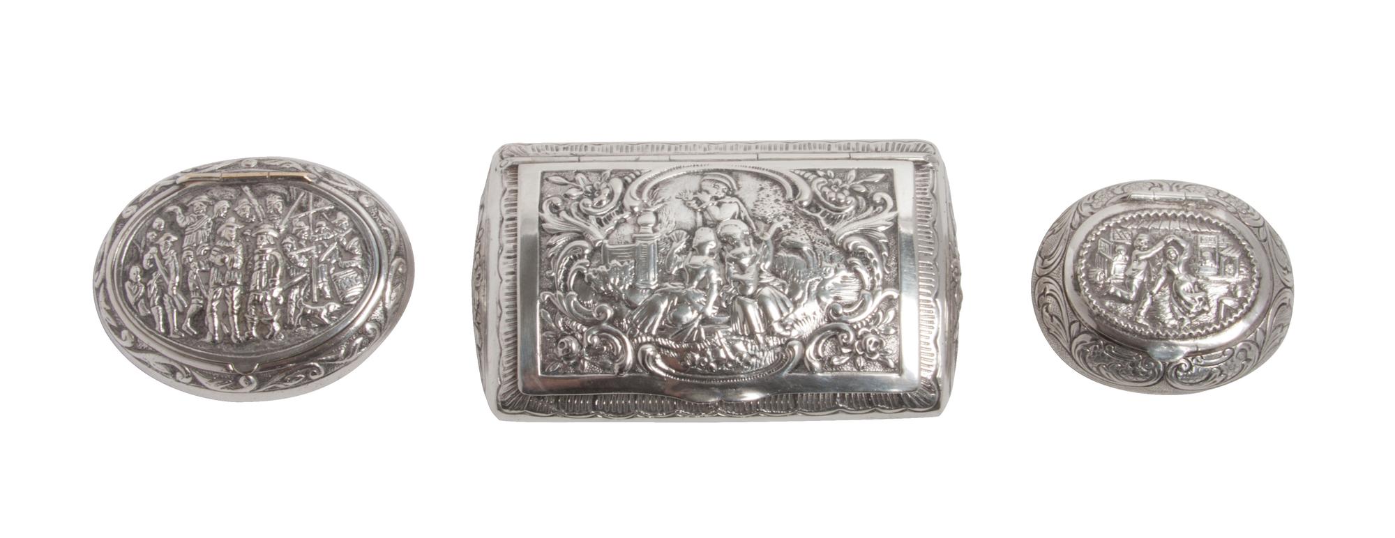 Three Silver Snuff Boxes, , one of rectangular form and two of oval form, having hinged lids chased with figural scenes and foliate scr