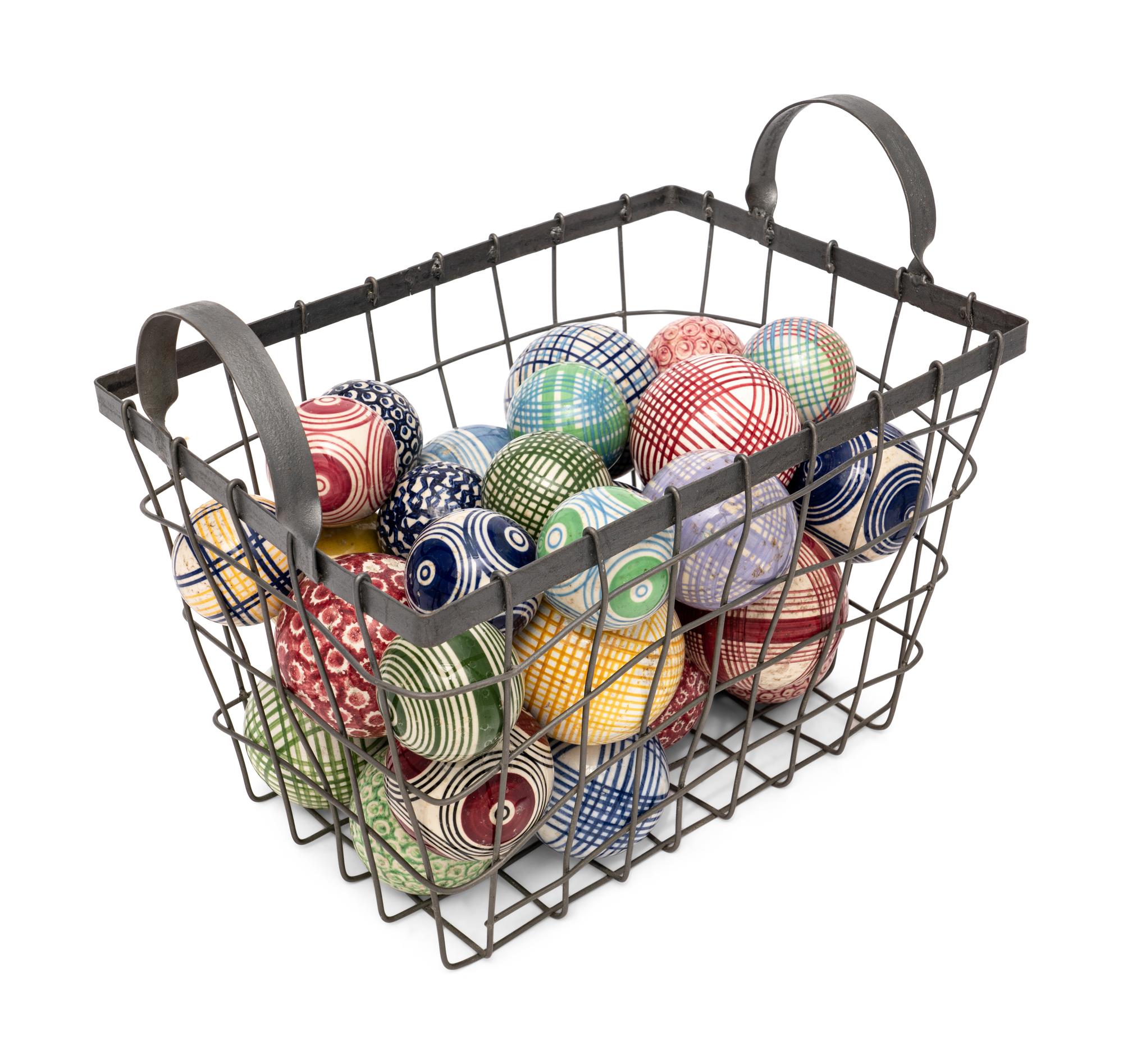 A Collection of English Polychrome Glazed Carpet Balls in a Wirework Basket