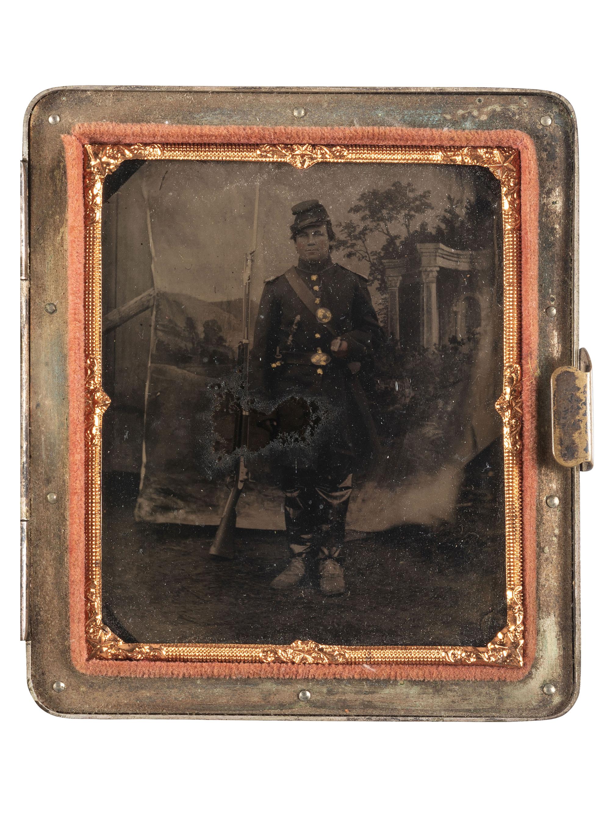 [CIVIL WAR]. Sixth plate tintype of an armed Union soldier posed before a Classically-inspired studio backdrop.