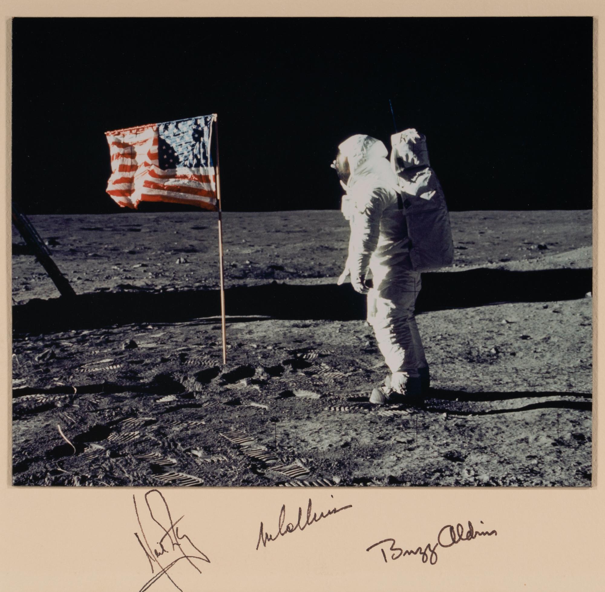 [NASA]. Photograph of Buzz Aldrin facing American flag on the moon, signed by crew members. 1969.