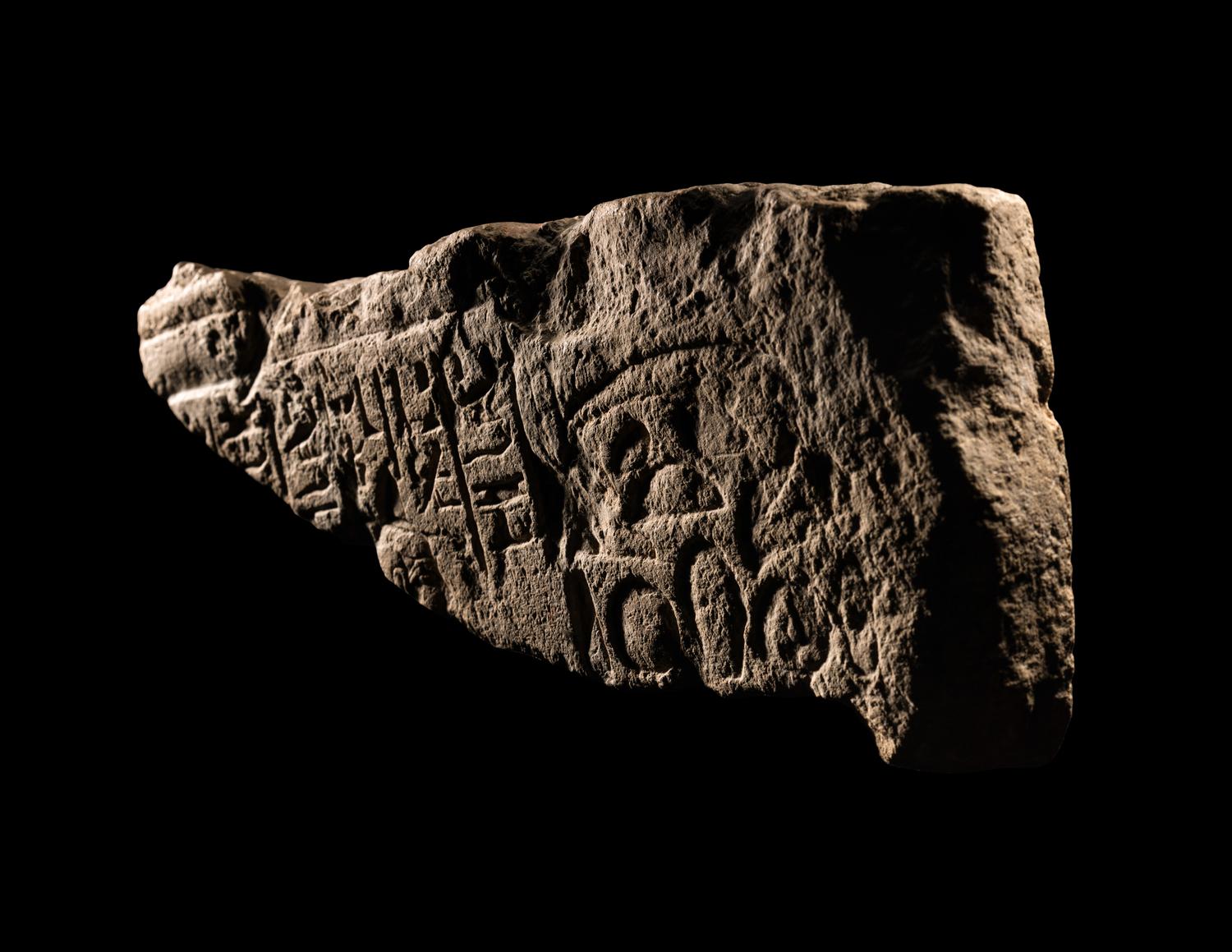 An Egyptian Limestone Relief Fragment Depicting an Attendant Wearing a Head-Cone