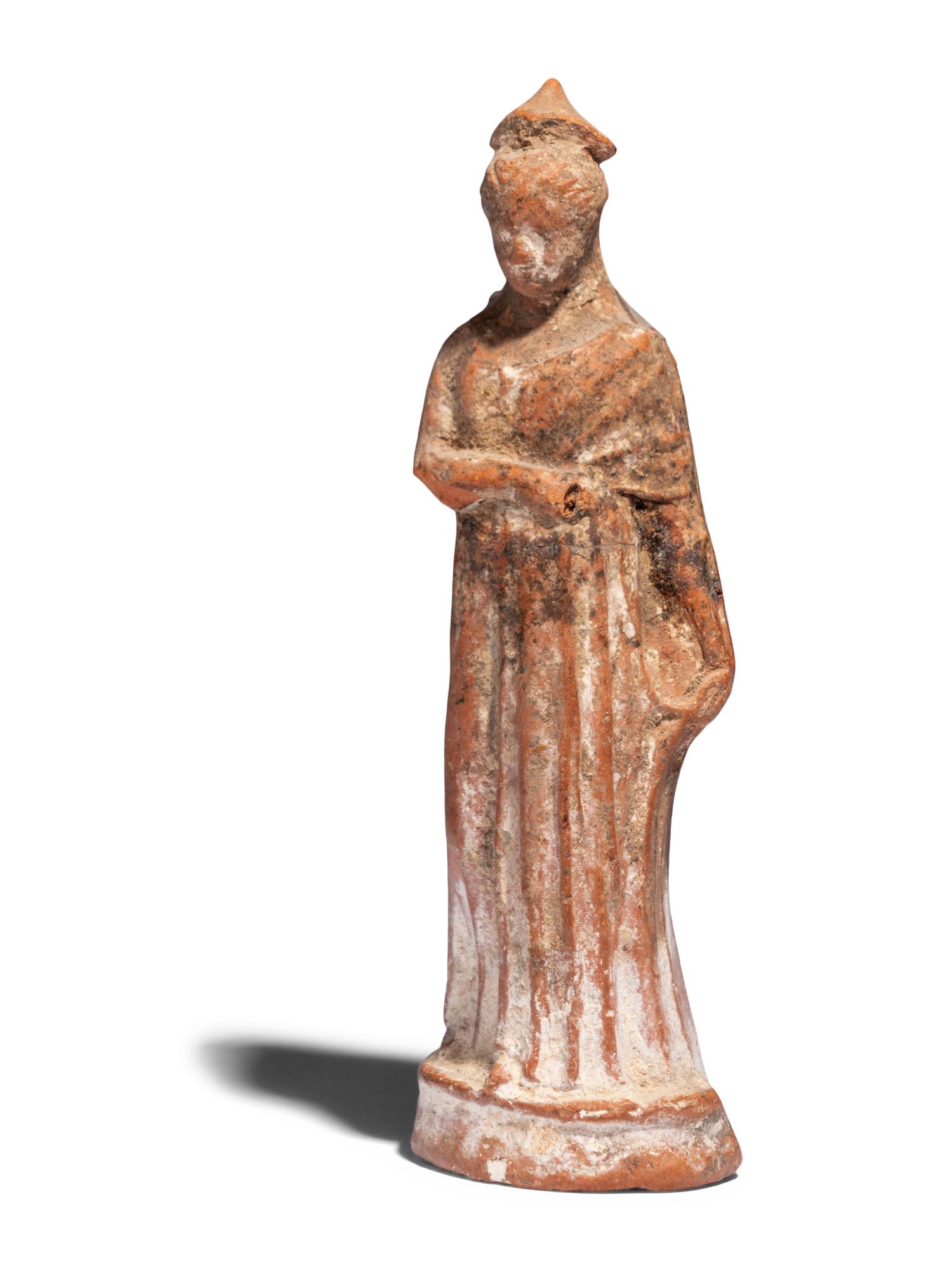 A Greek Terracotta Draped Female Figure with a Pilos