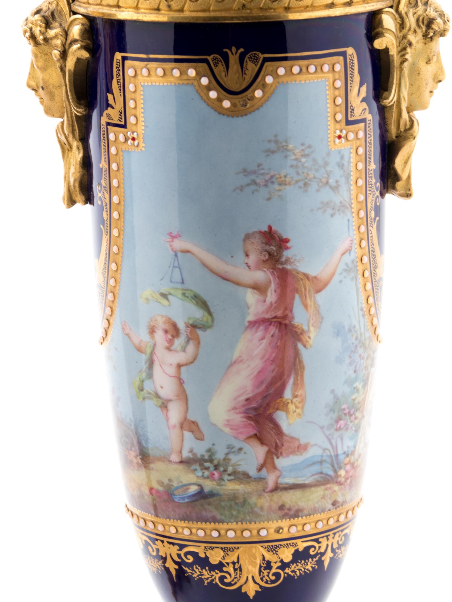 A Pair of Sèvres Style Gilt Bronze Mounted Painted, Parcel Gilt and "Jeweled" Porcelain Urns