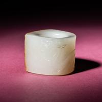 A Chinese Russet and White Jade 'Taotie and Chilong' Archer's Ring, 18th Century — 清中期 白玉留皮饕餮螭龍紋扳指