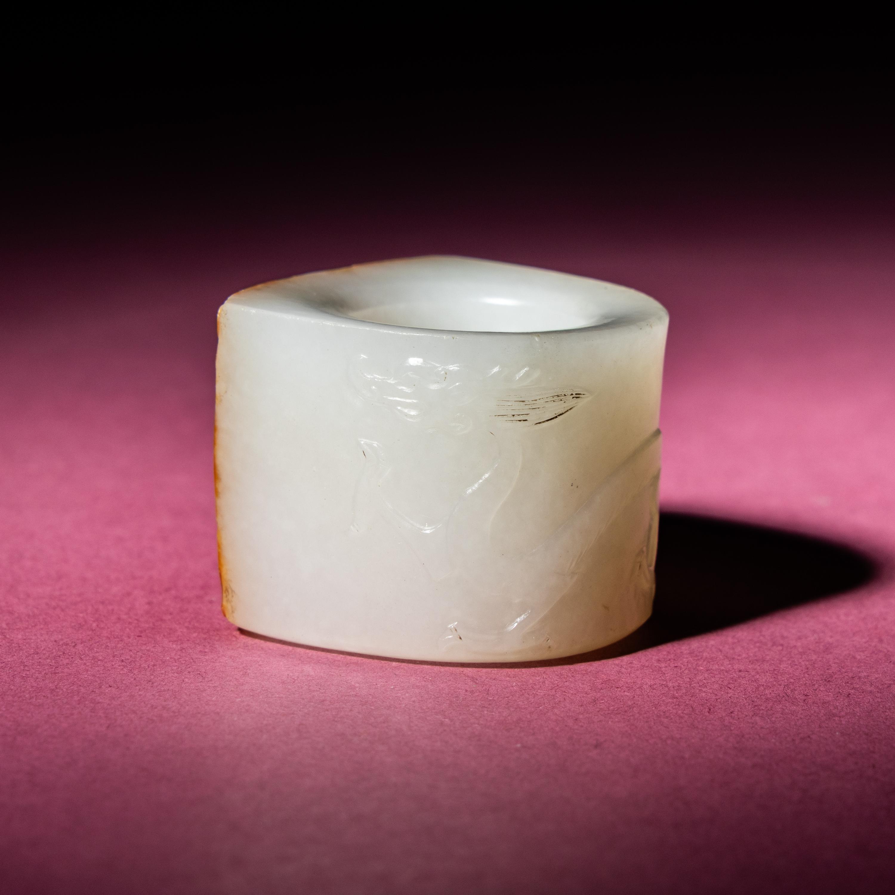 A Chinese Russet and White Jade 'Taotie and Chilong' Archer's Ring, 18th Century — 清中期 白玉留皮饕餮螭龍紋扳指