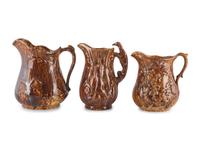 Seven Molded Yellowware Pitchers in Rockingham Glaze
