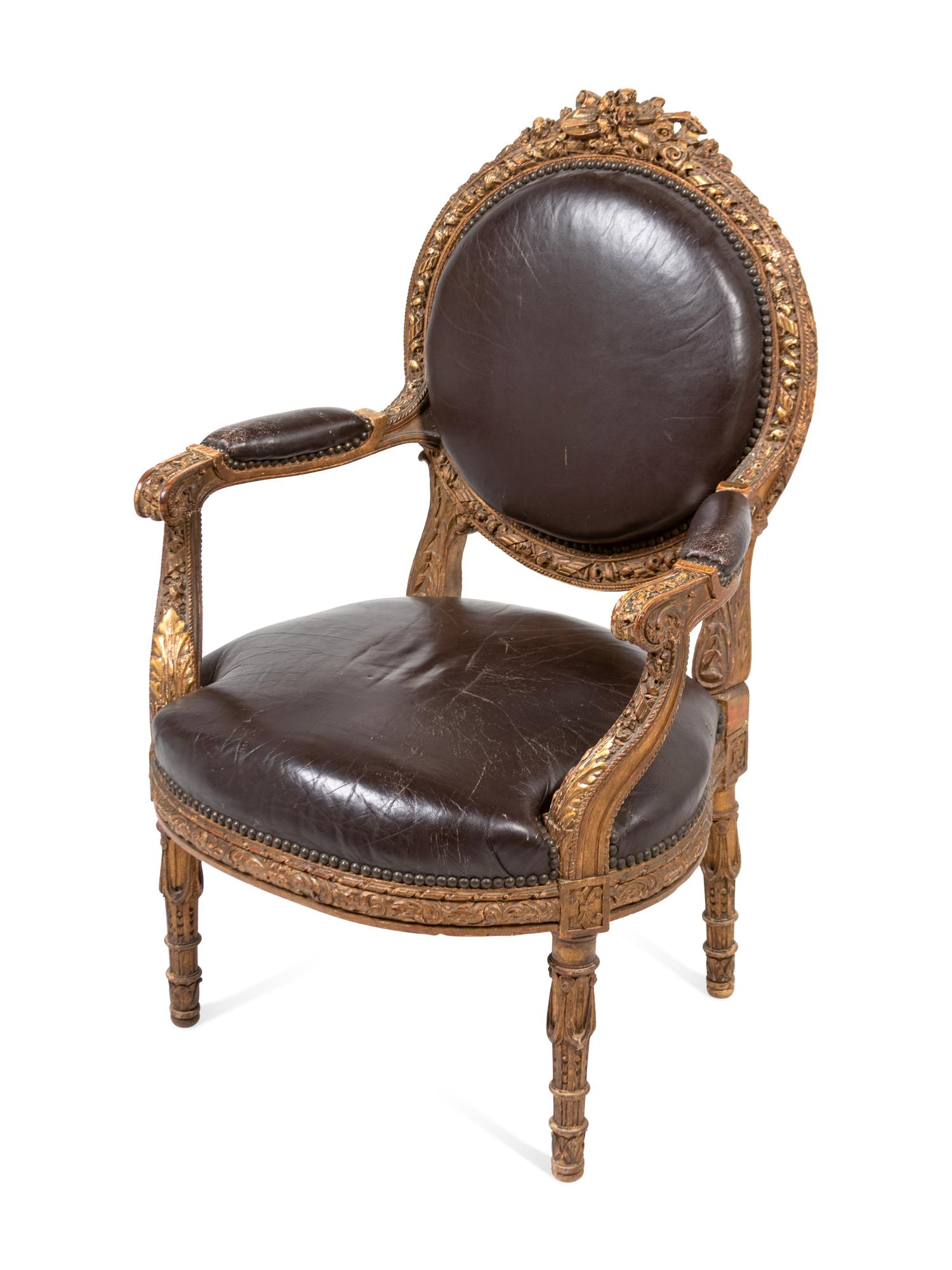A Louis XVI Style Leather Upholstered and Parcel Gilt Fauteuil