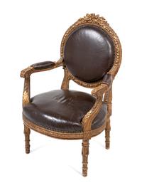 A Louis XVI Style Leather Upholstered and Parcel Gilt Fauteuil