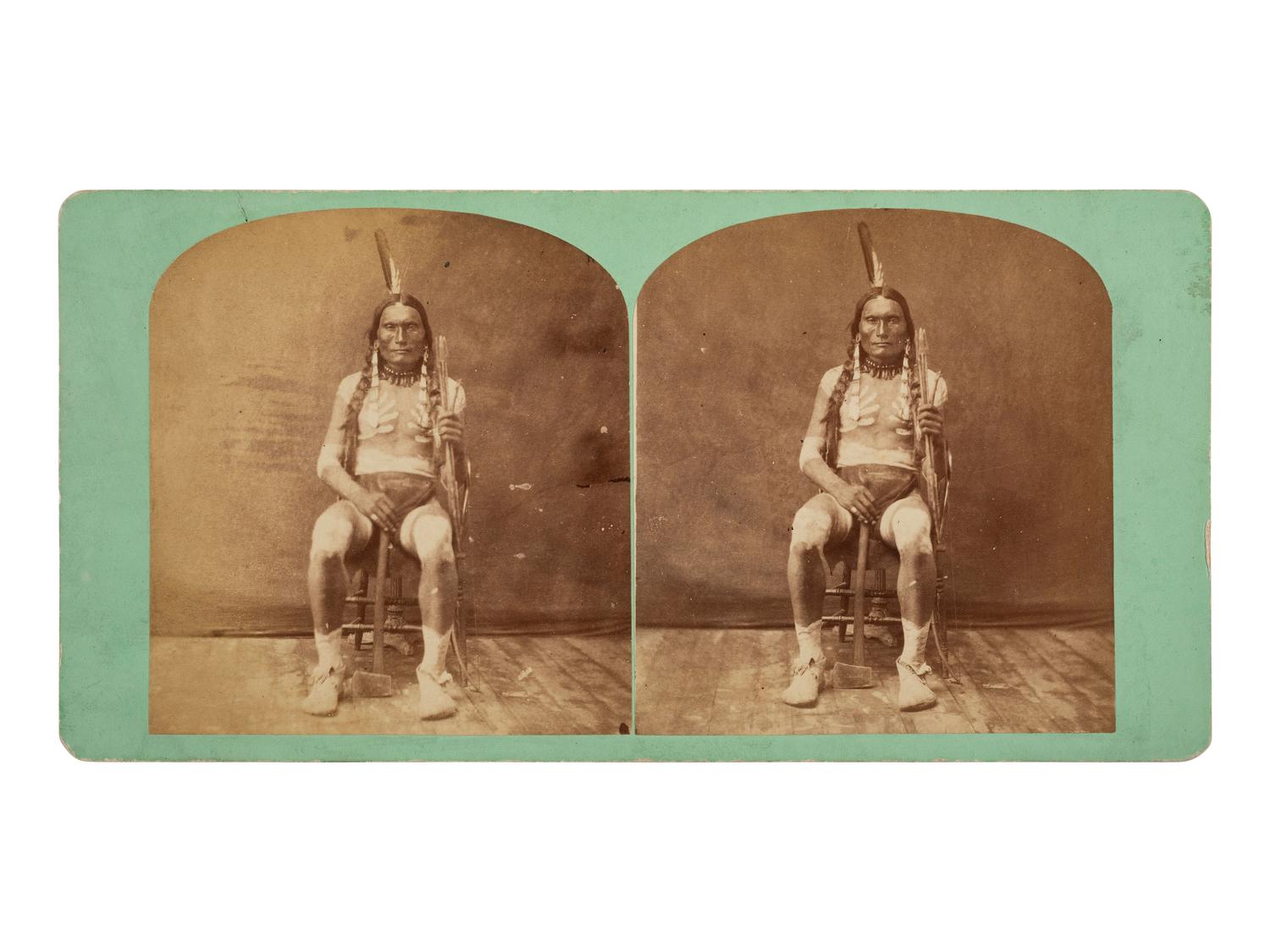 [NATIVE AMERICANS]. MORROW, Stanley J. (1843-1921), photographer. Stereoview of a Sioux subject with tomahawk and arrows.