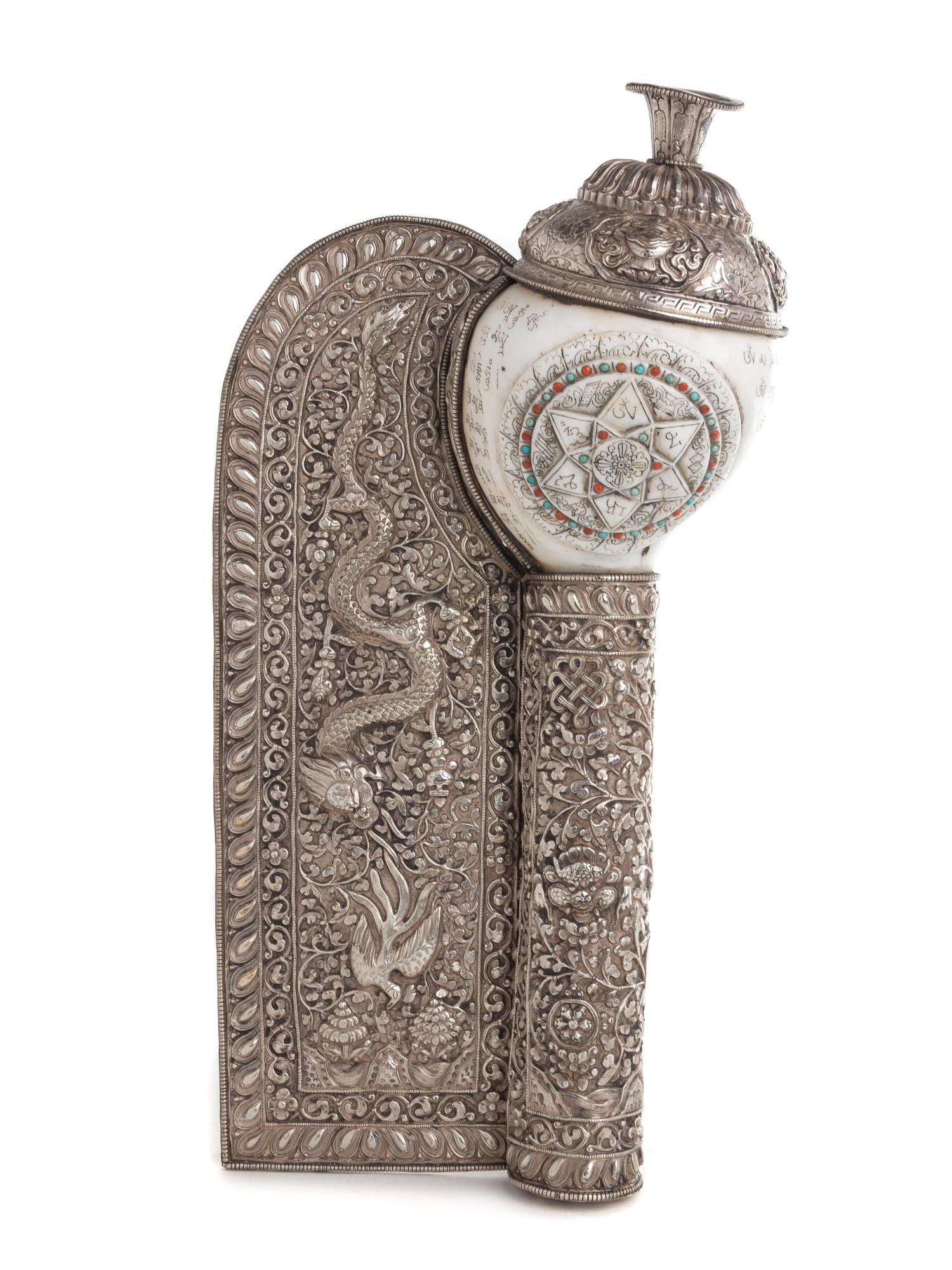A Tibetan Silvered Metal Mounted and Carved Conch Shell Length 16 inches.