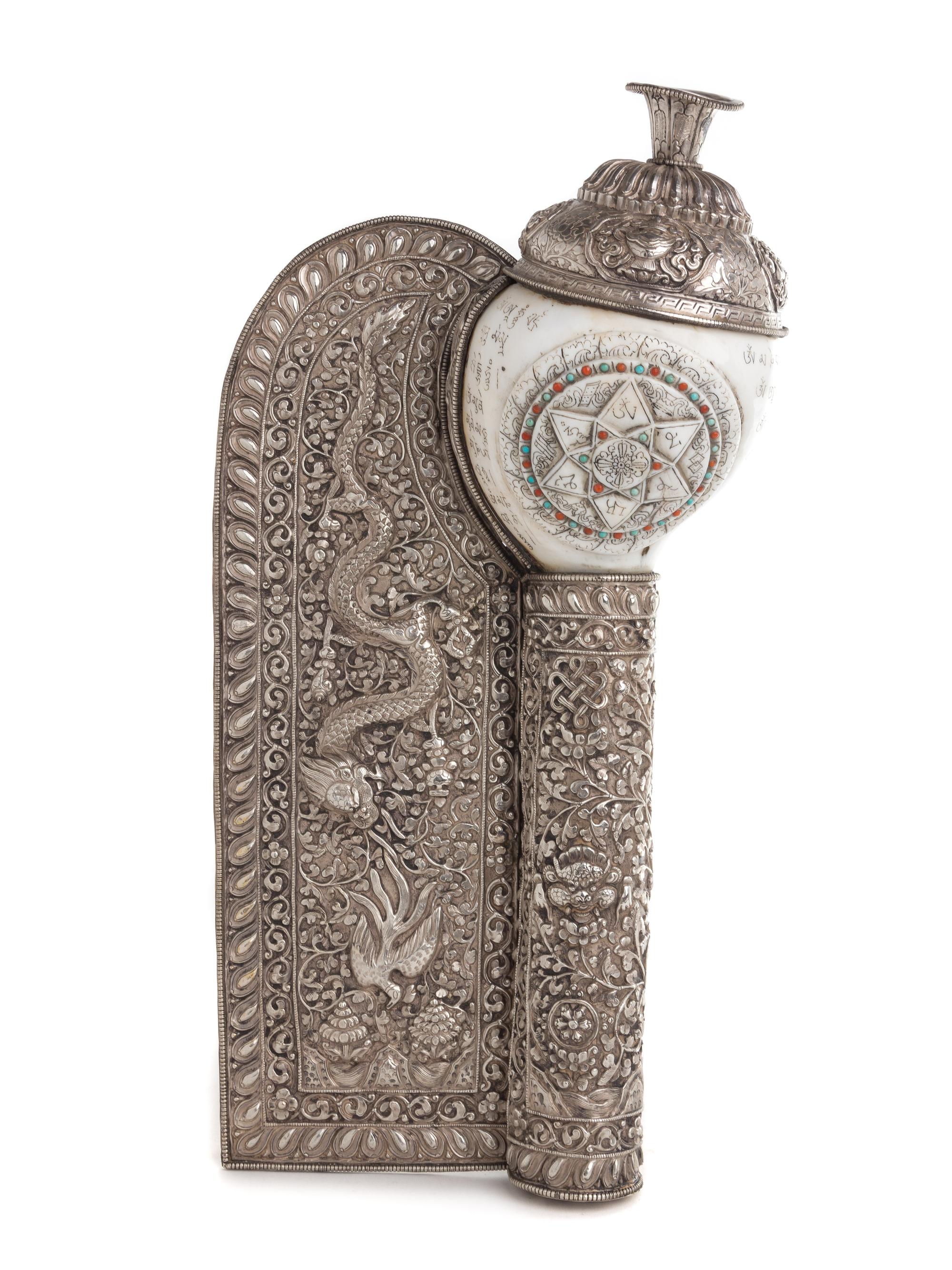 A Tibetan Silvered Metal Mounted and Carved Conch Shell Length 16 inches.