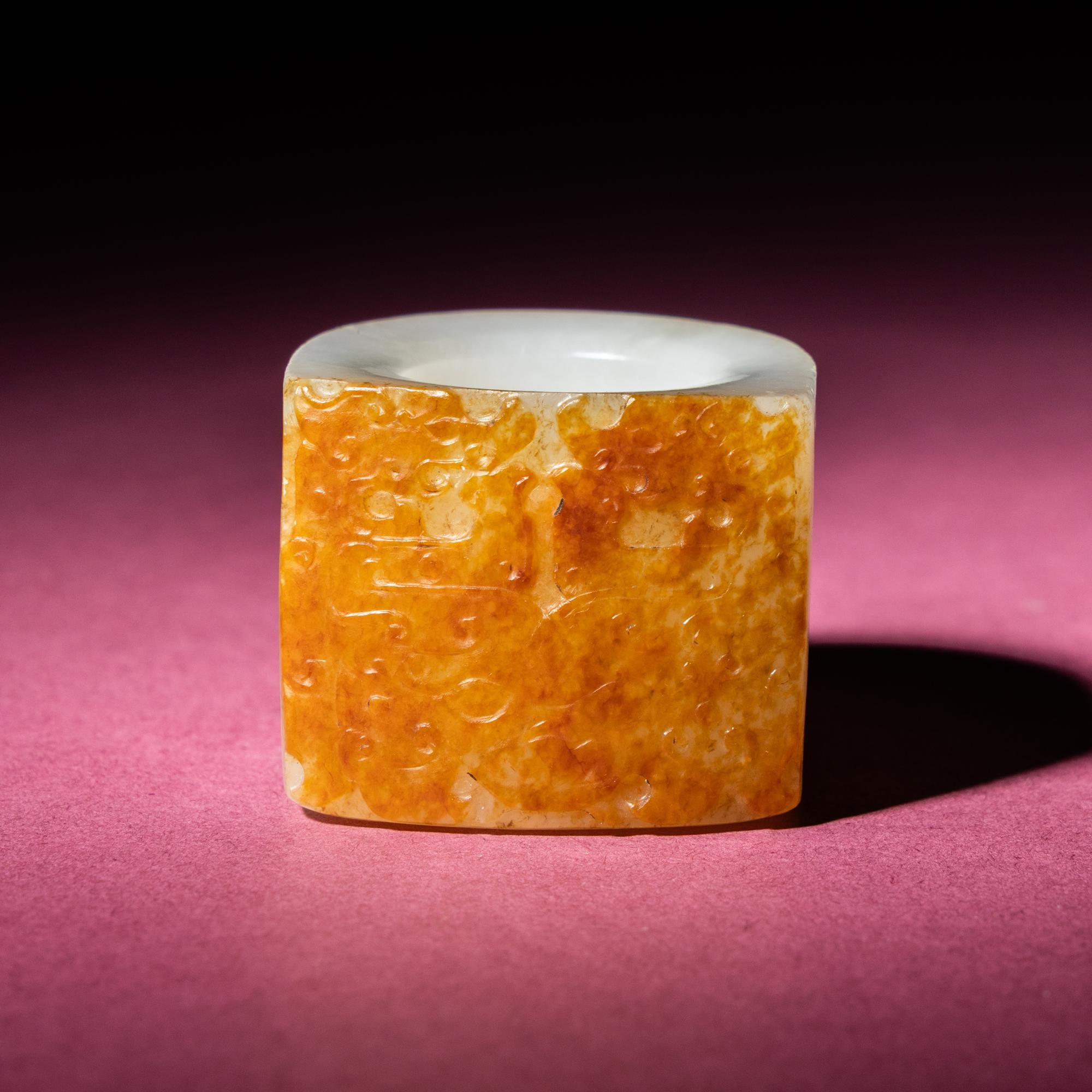A Chinese Russet and White Jade 'Taotie and Chilong' Archer's Ring, 18th Century — 清中期 白玉留皮饕餮螭龍紋扳指
