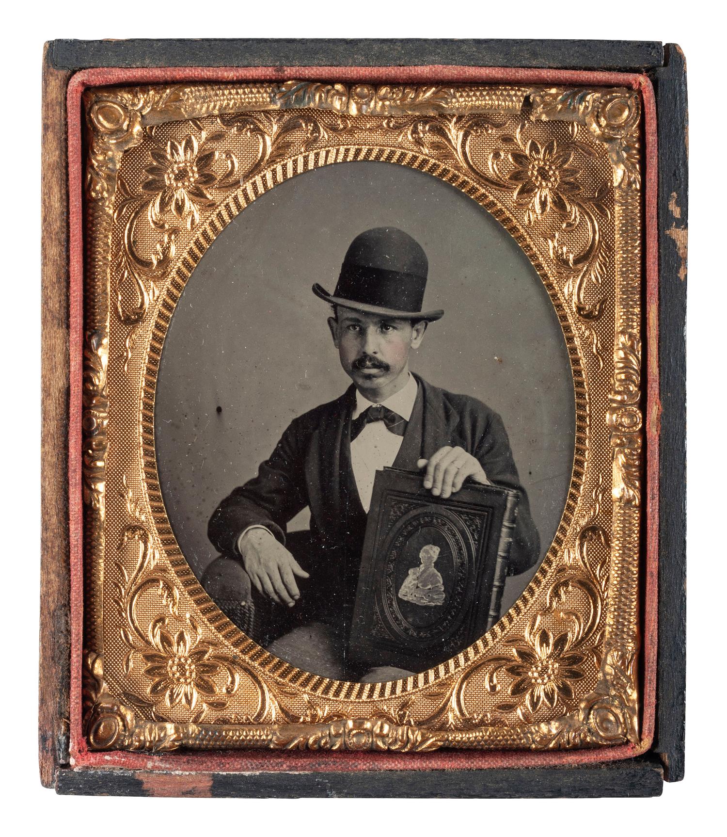 [EARLY PHOTOGRAPHY]. Sixth plate tintype of mustachioed man displaying a large book.