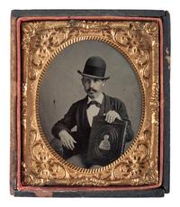 [EARLY PHOTOGRAPHY]. Sixth plate tintype of mustachioed man displaying a large book.