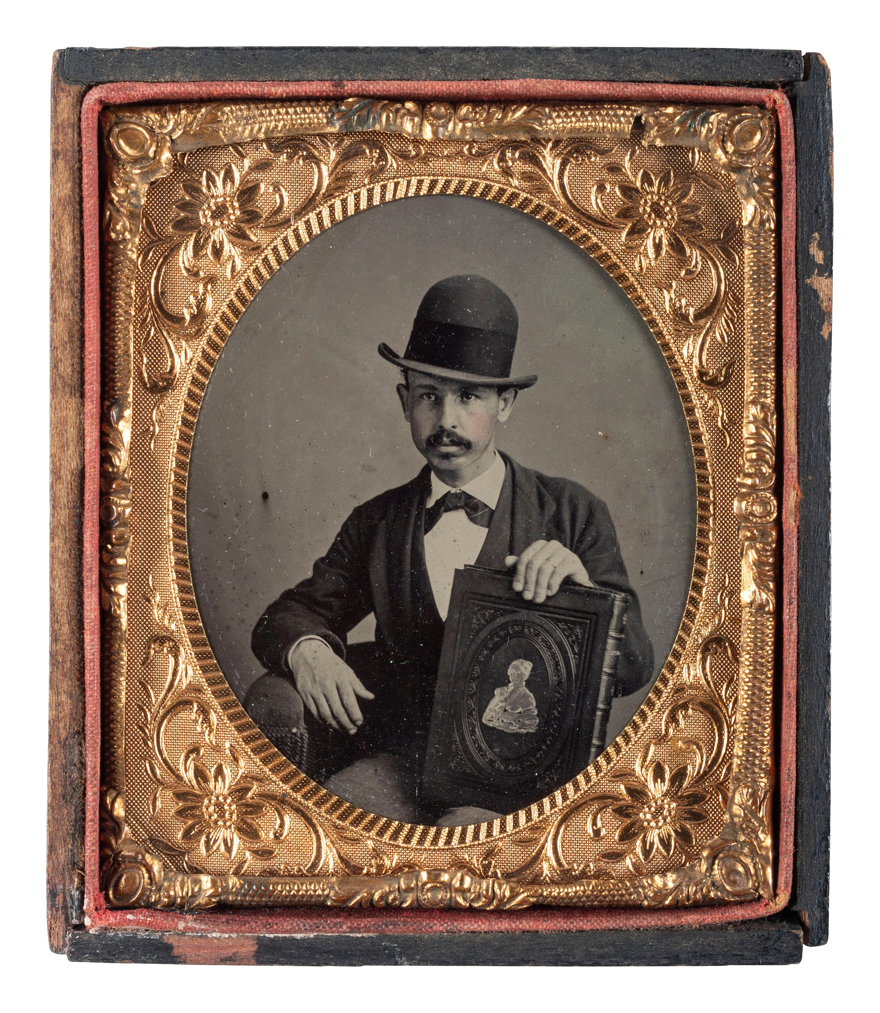 [EARLY PHOTOGRAPHY]. Sixth plate tintype of mustachioed man displaying a large book.