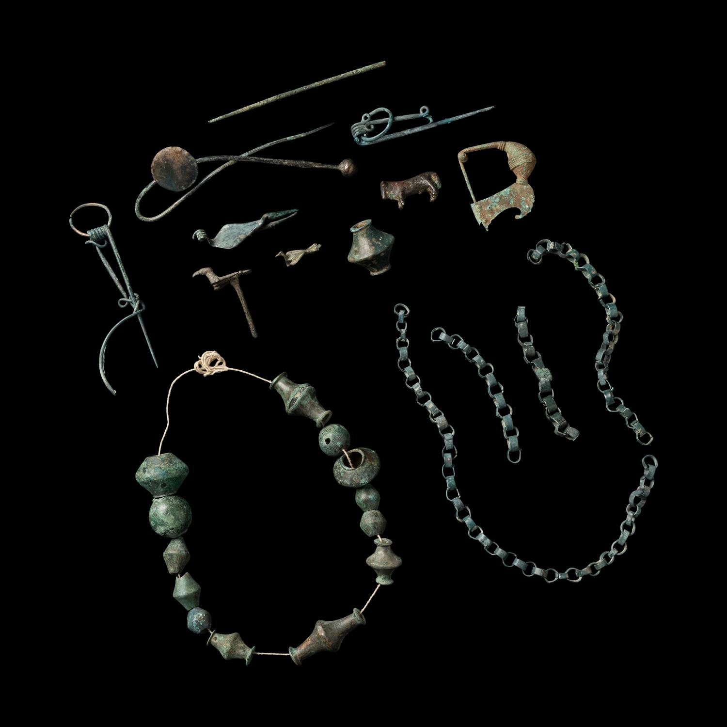 A Group of European and Luristan Bronze Fragmentary Fibulae, Beads, and Chains