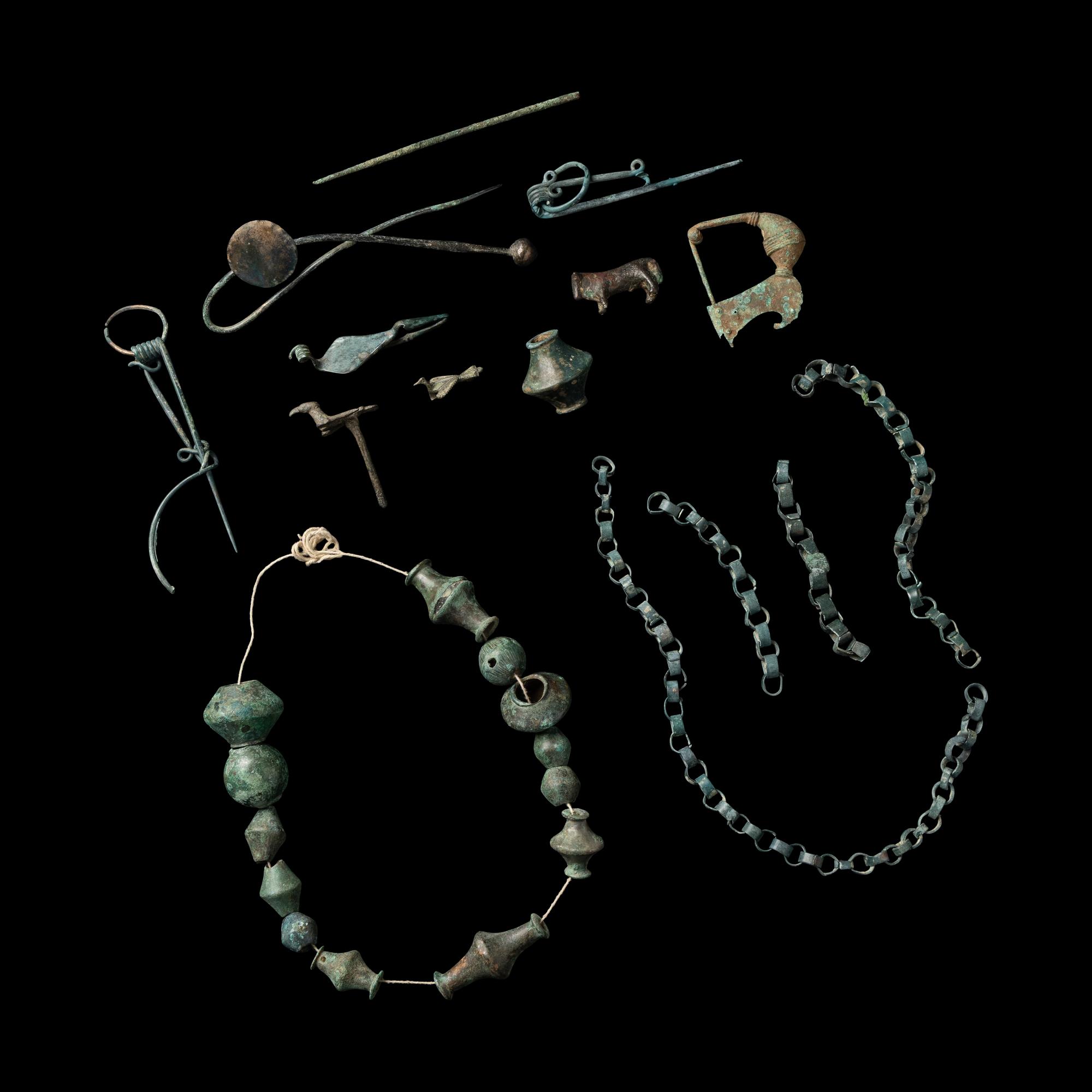 A Group of European and Luristan Bronze Fragmentary Fibulae, Beads, and Chains