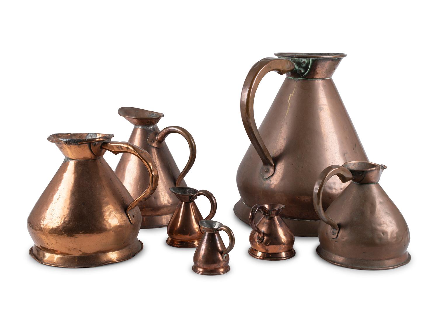 Seven Copper Graduated Pitchers