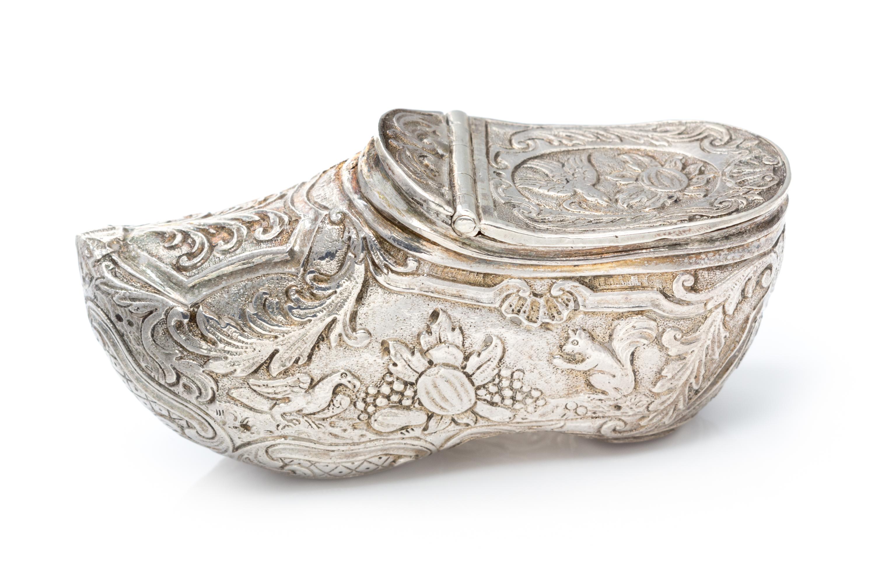 A German Silver Vinaigrette, Maker's Mark Obscured, in the form of a shoe, the exterior chased with floral, foliate and fauna decoratio
