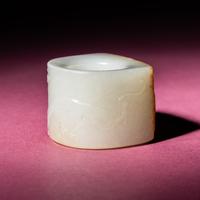 A Chinese Russet and White Jade 'Taotie and Chilong' Archer's Ring, 18th Century — 清中期 白玉留皮饕餮螭龍紋扳指
